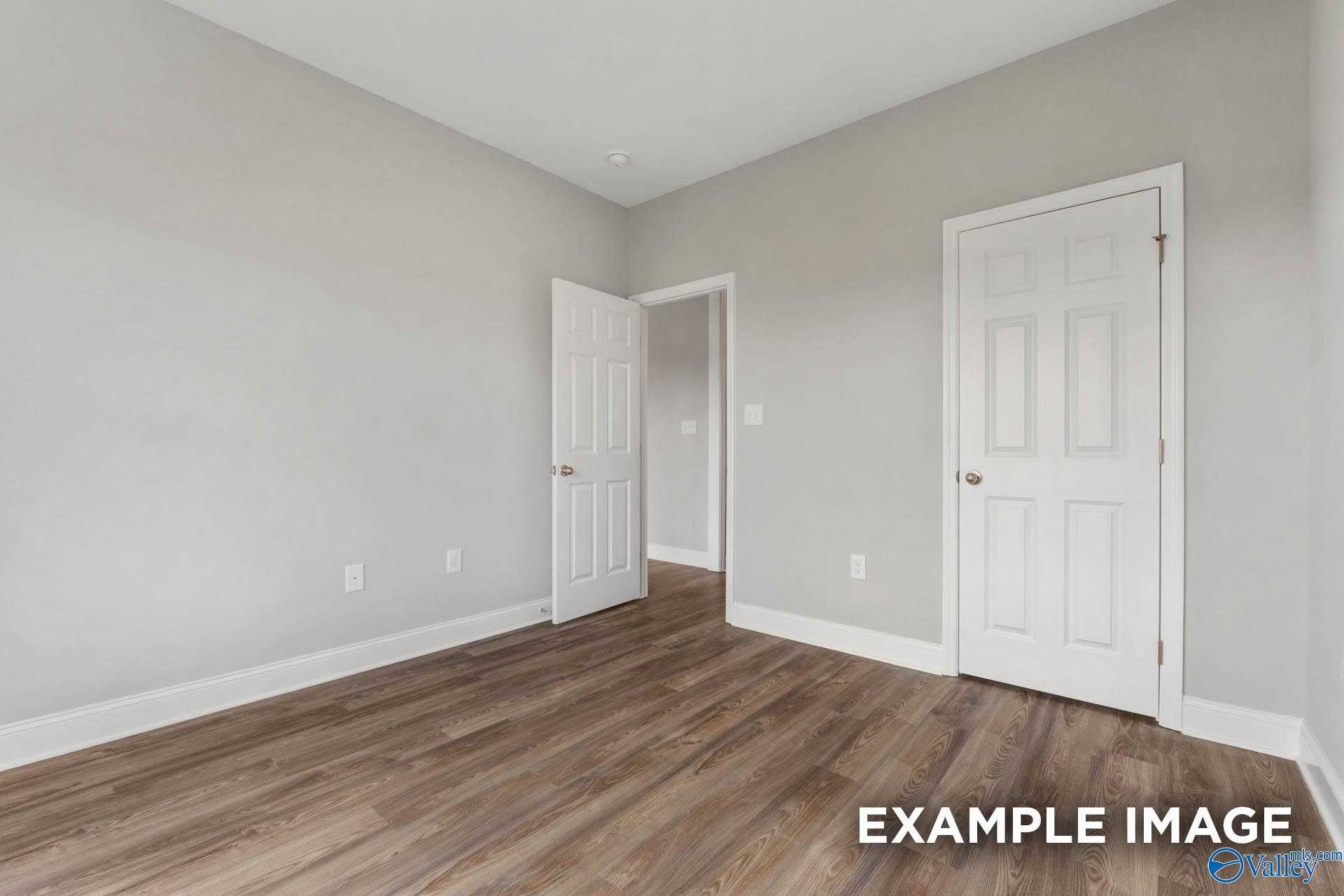Bright secondary bedroom with light gray walls, white doors, and hardwood floors in The Shelby B, Athens, Alabama