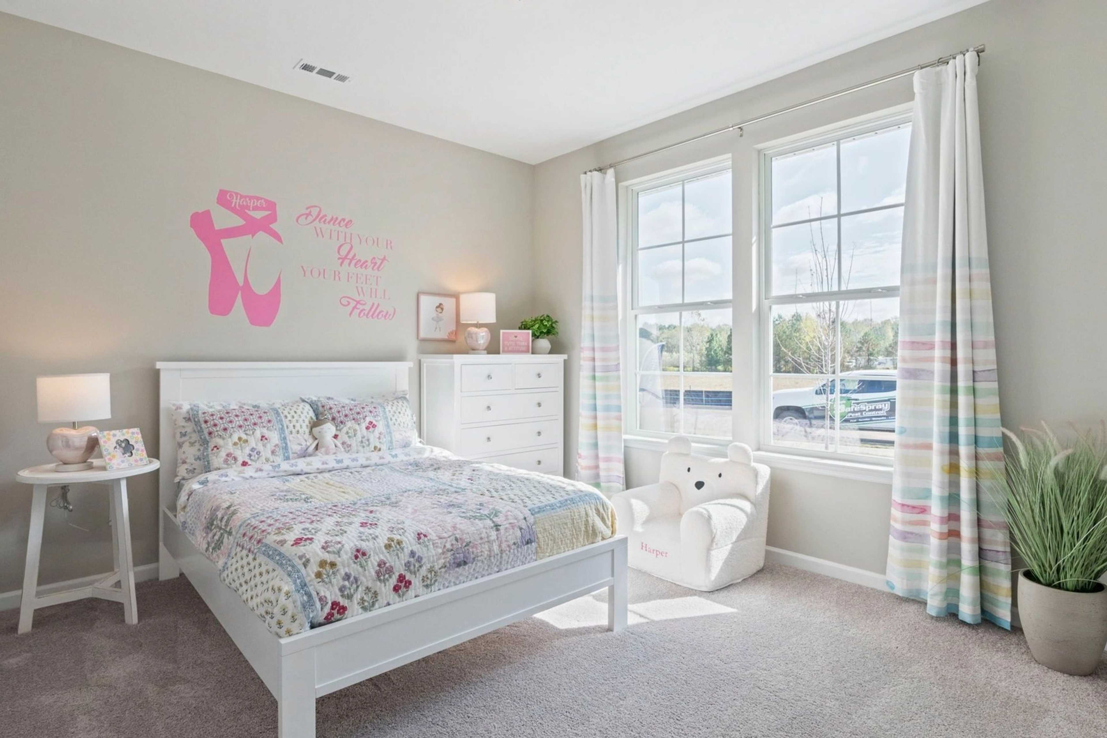 Cozy ballet-themed girl's bedroom in Bailey Park Fayetteville TN with white bed, colorful quilt, wall art and window light