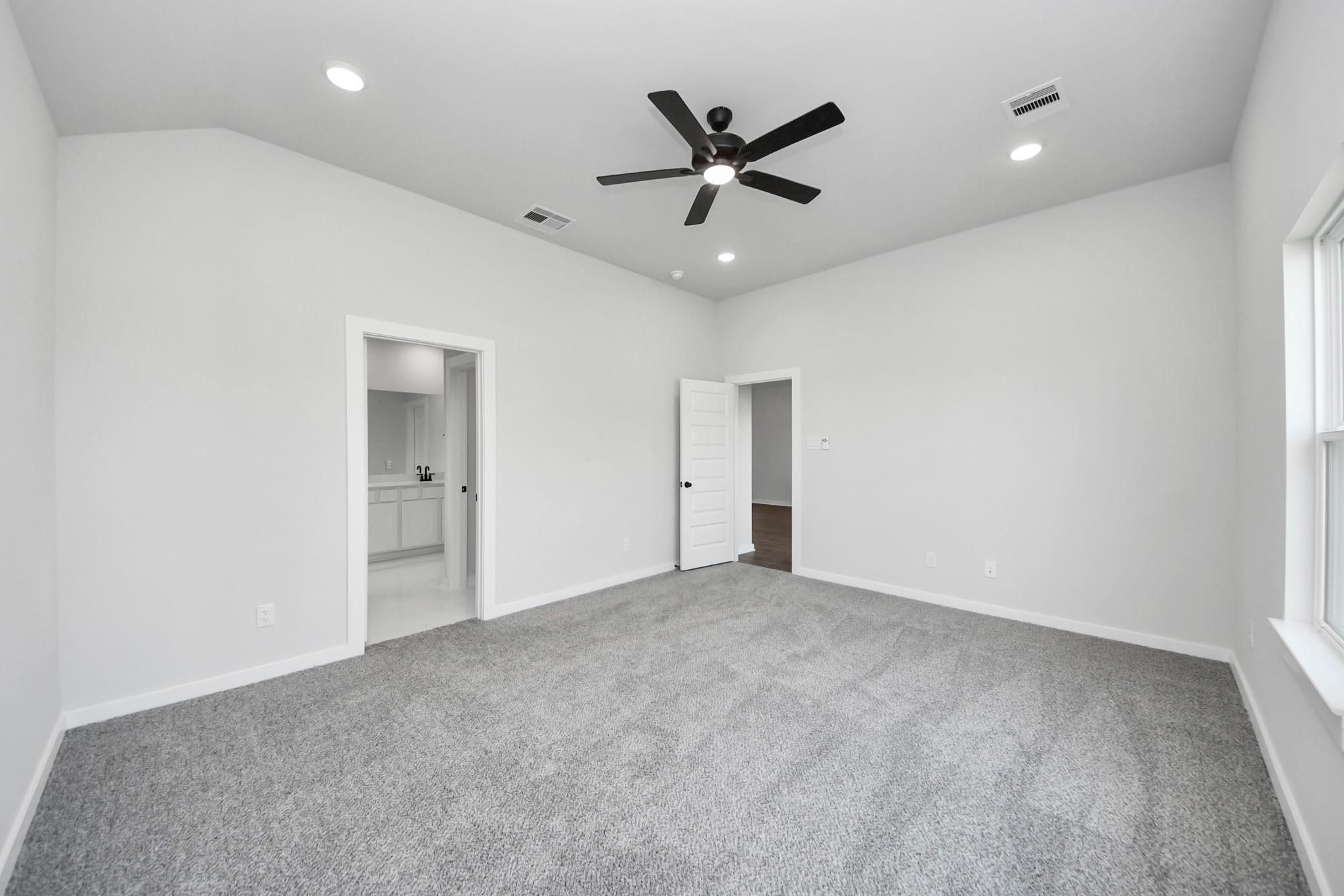 Spacious primary bedroom with vaulted ceiling in The Riviera C floor plan at River Ranch Meadows, Dayton, Texas.
