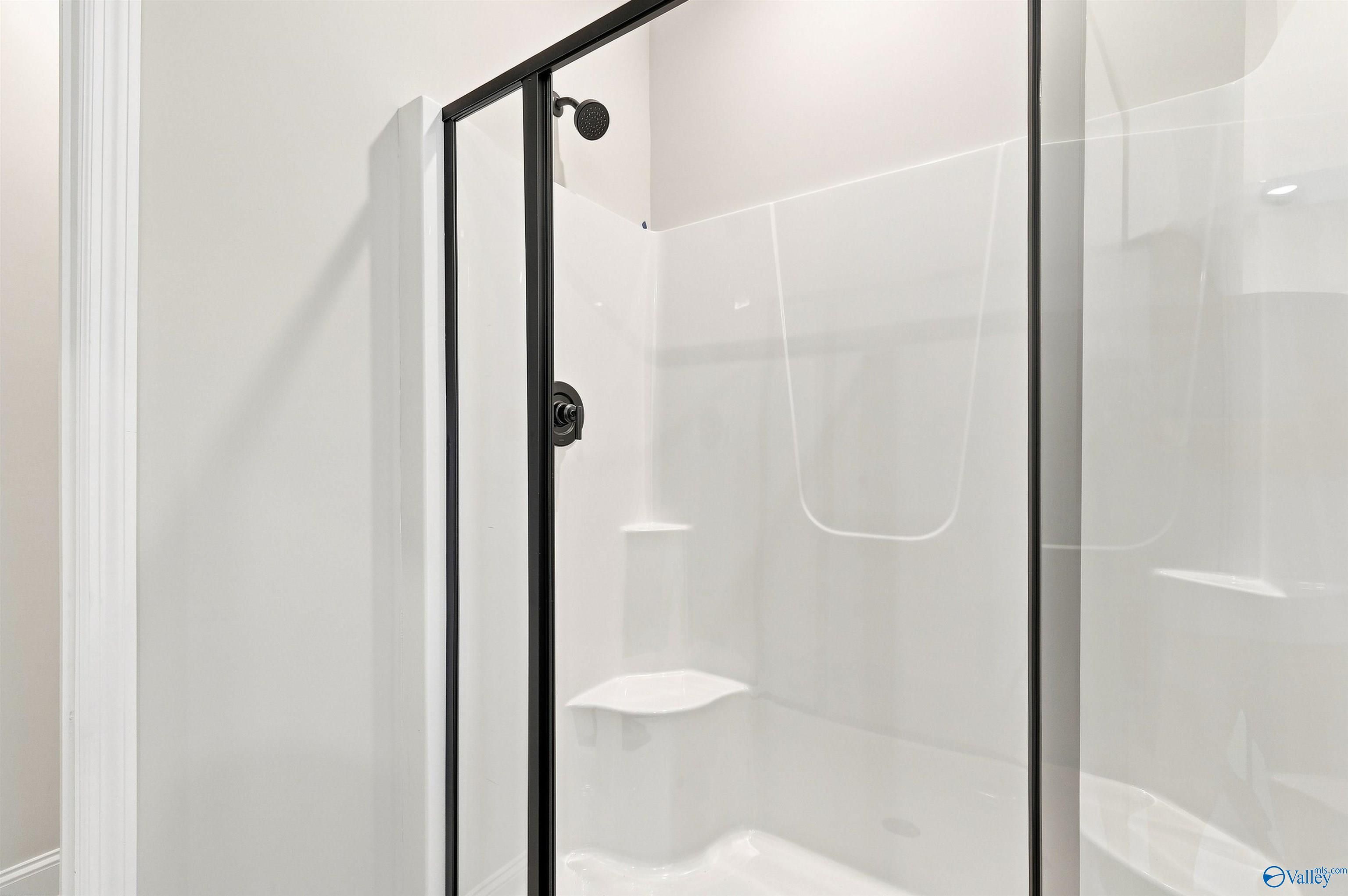 Modern walk-in shower with black frame and white surround in The Daphne floor plan by Davidson Homes in Huntsville, Alabama.
