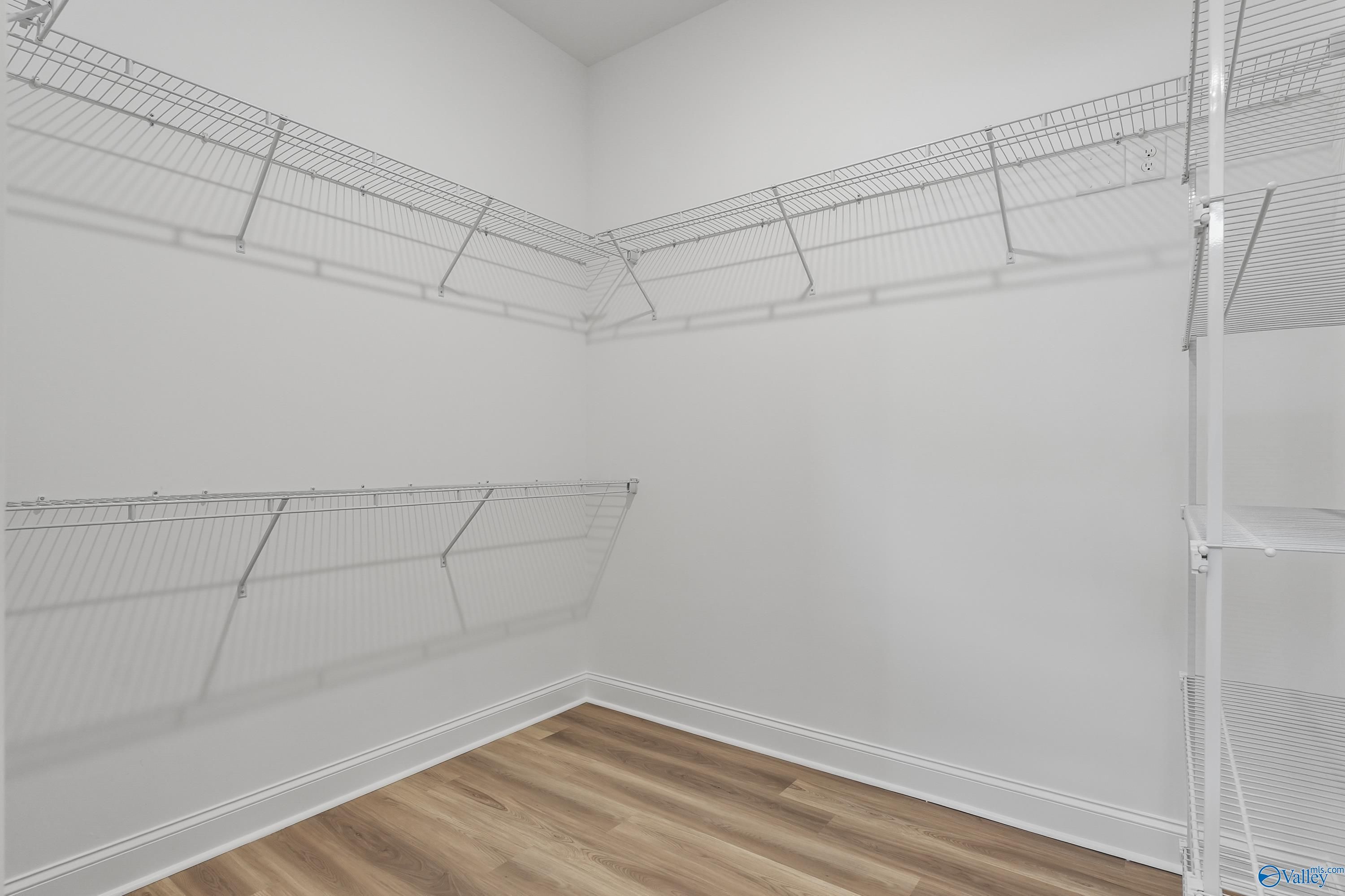 Spacious walk-in closet featuring wire shelving and wood flooring in Evermore Homes The Haven, Owens Cross Roads, Alabama
