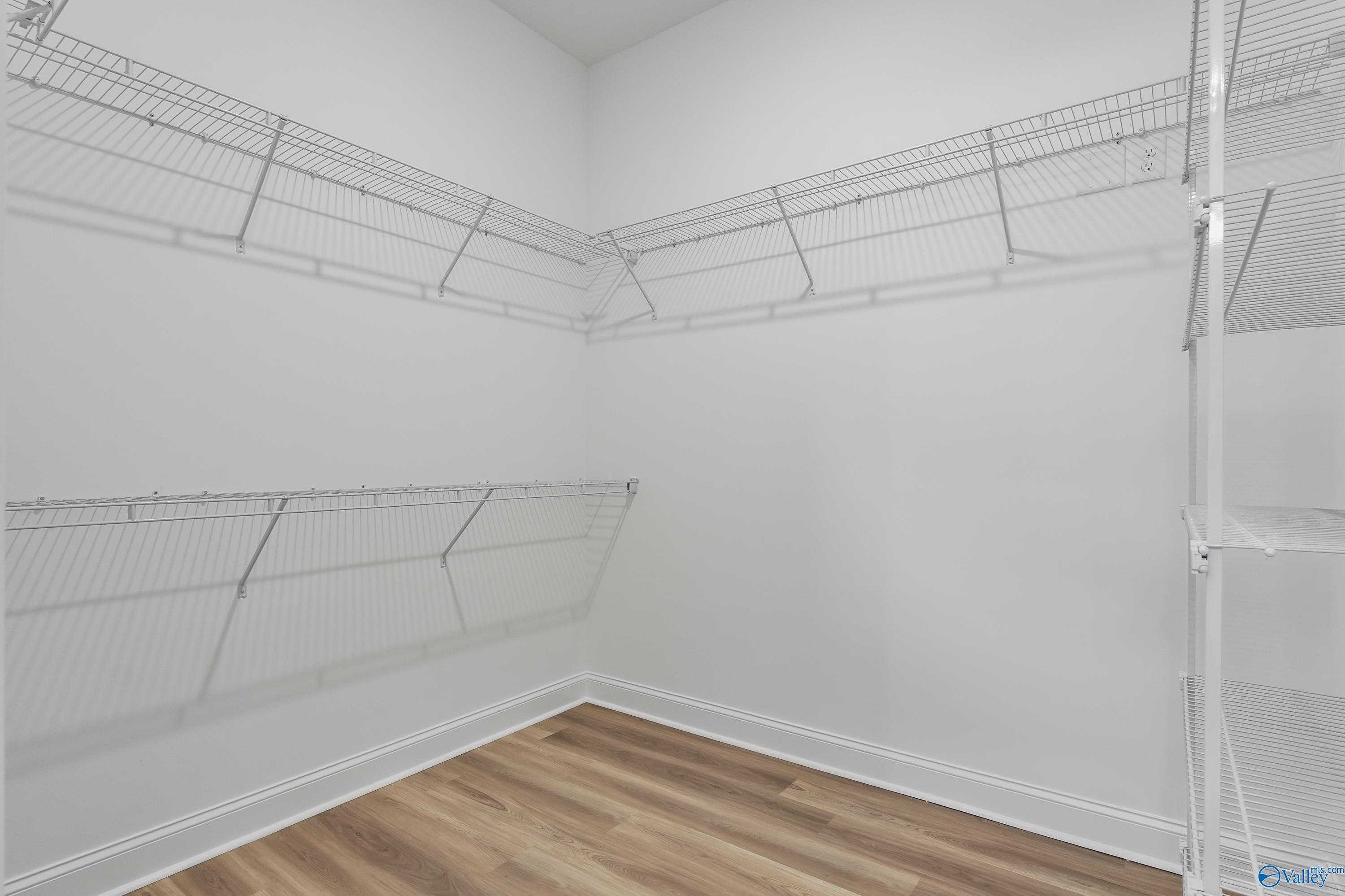 Spacious walk-in closet featuring wire shelving and wood flooring in Evermore Homes The Haven, Owens Cross Roads, Alabama
