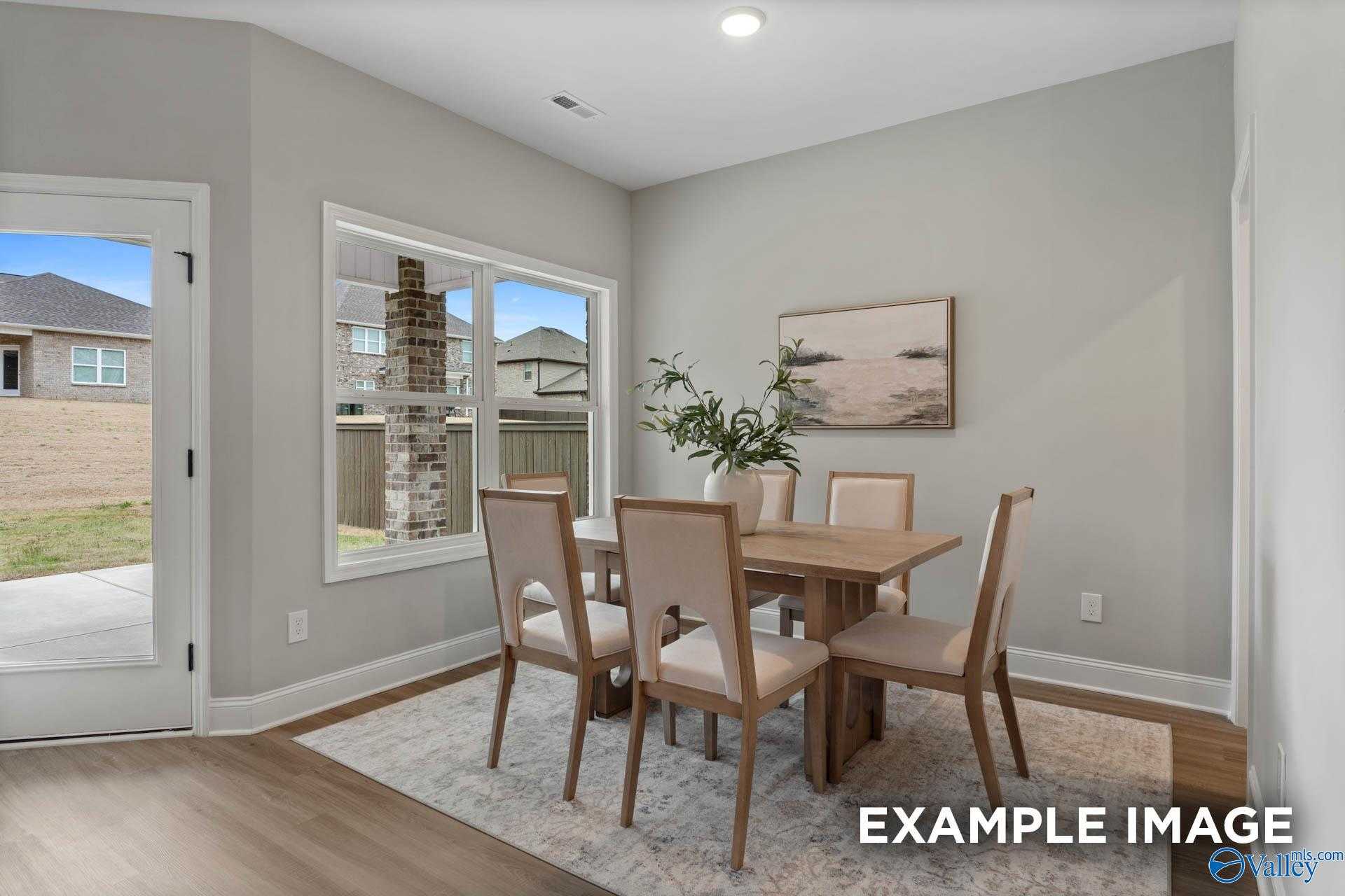 Elegant dining room with wooden table, beige chairs, large windows to backyard in Davidson Homes The Daphne C, Owens Cross Roads
