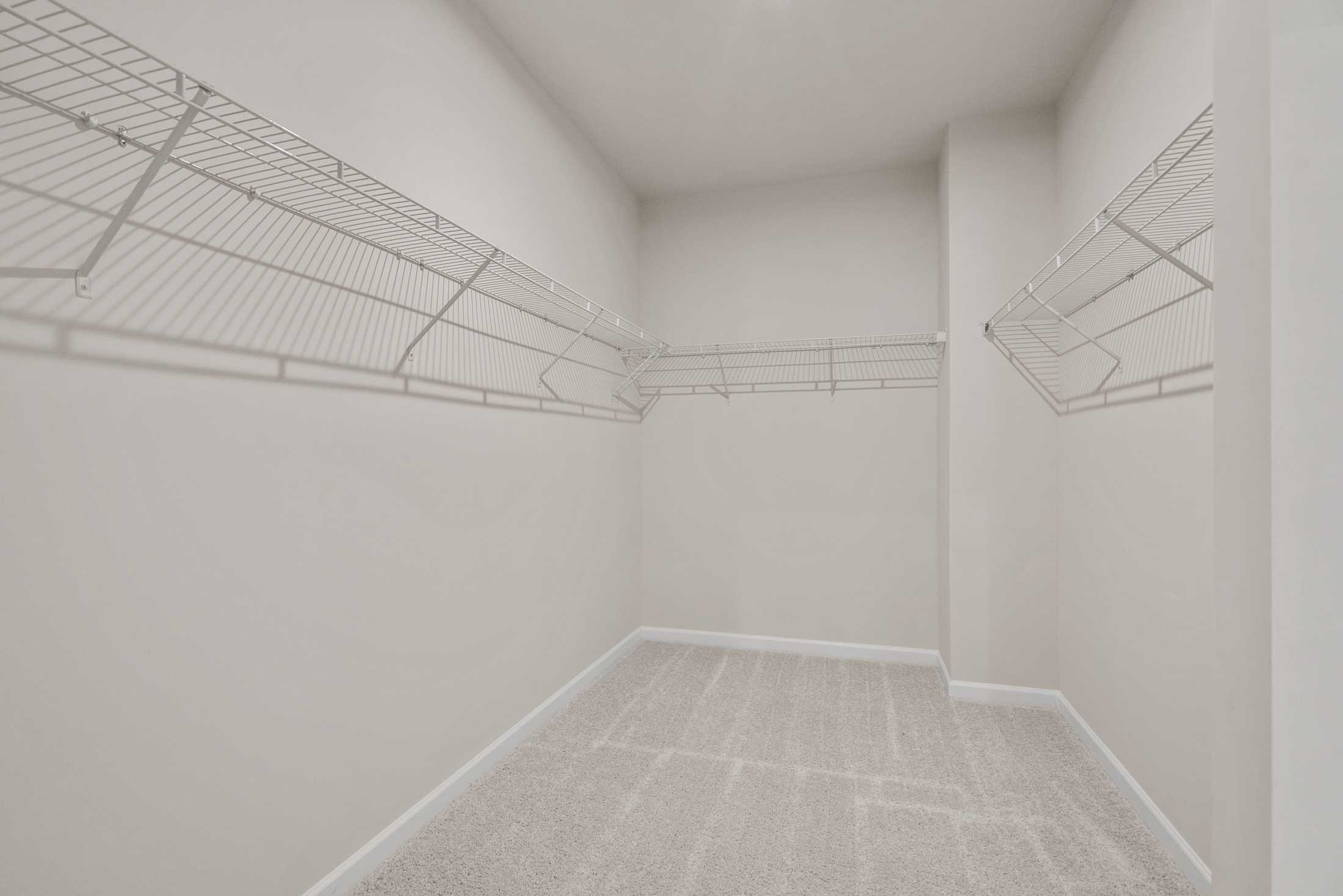 Spacious walk-in closet in The Dawson C master suite with wire shelving, beige walls, and carpeted floor