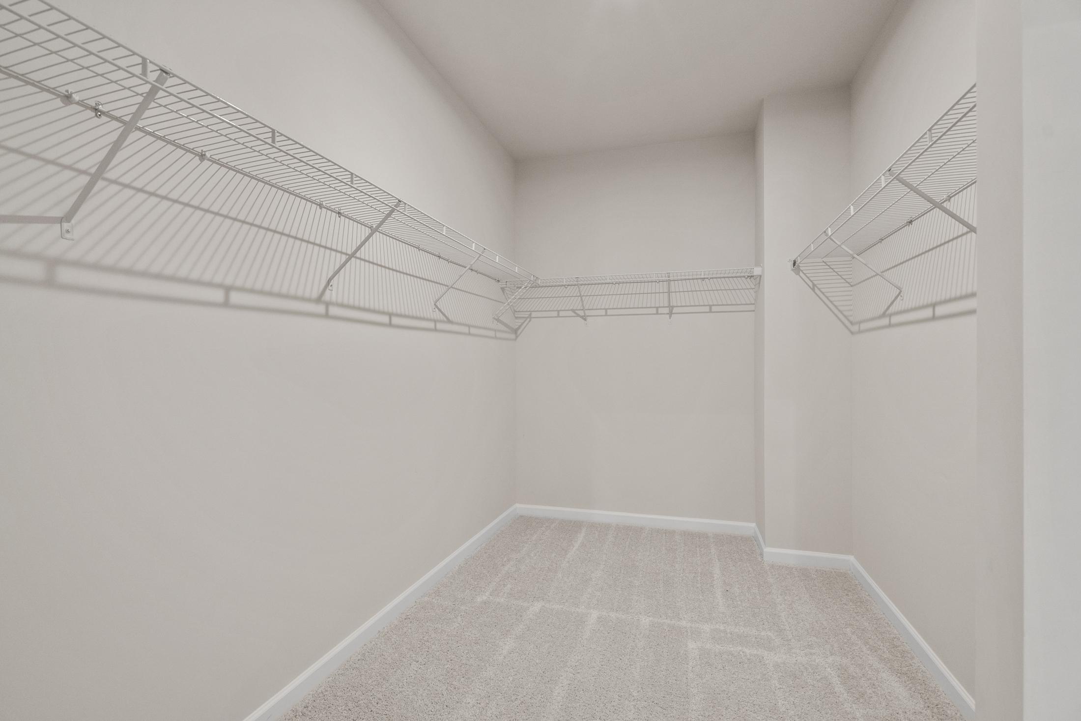 Spacious walk-in closet in The Dawson C master suite with wire shelving, beige walls, and carpeted floor
