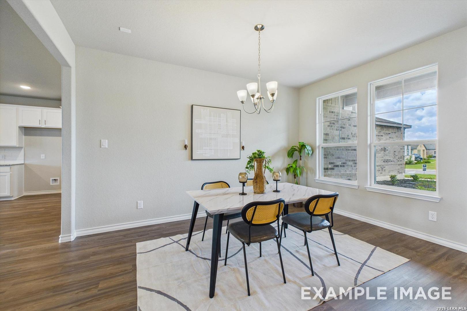 Modern dining area with marble-top table and wicker chairs in The Foster F floor plan at Potranco Oaks, Castroville, TX.