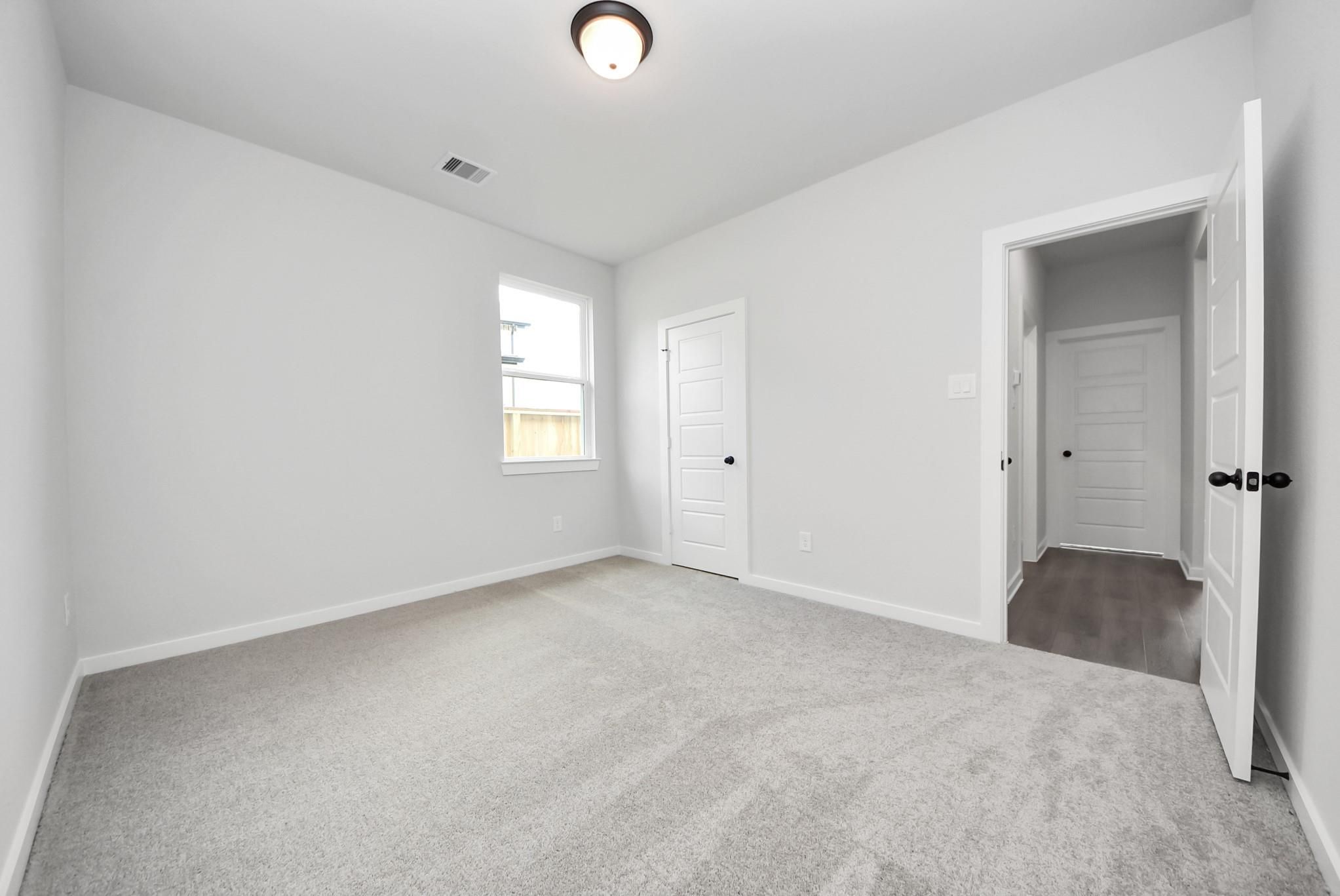 Bright, spacious secondary bedroom with plush carpet in The Daphne F floor plan at Sundance Cove, Crosby, Texas.