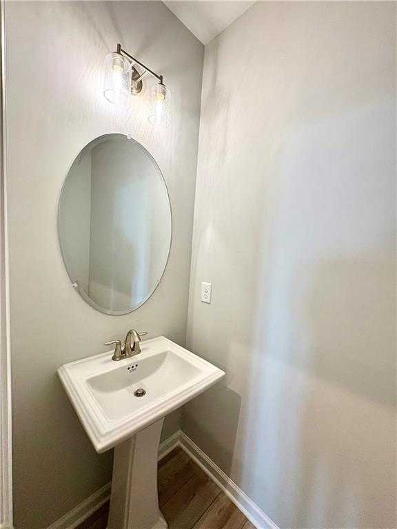 Elegant powder room featuring oval mirror, pedestal sink, and brass lighting in Davidson Homes The Monroe A, Emerson, Georgia