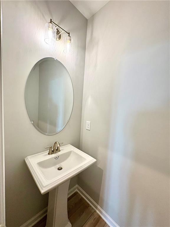 Elegant powder room featuring oval mirror, pedestal sink, and brass lighting in Davidson Homes The Monroe A, Emerson, Georgia