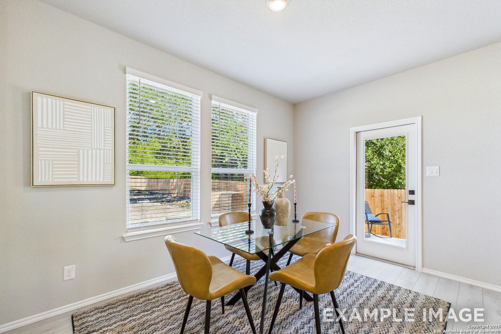 Modern dining room with glass table, leather chairs, large windows overlooking backyard in Davidson Homes The Charlotte A, San Antonio