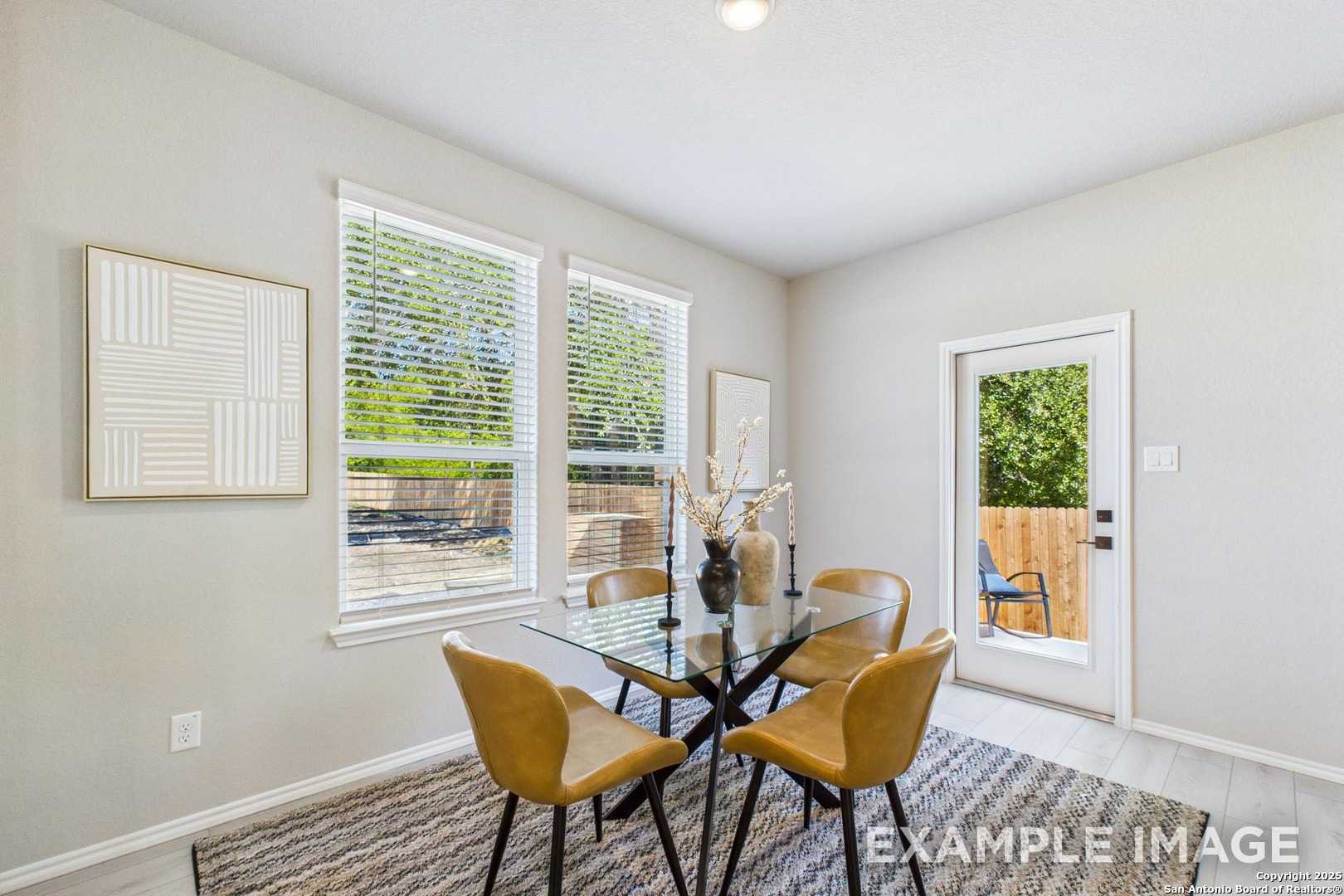 Modern dining room with glass table, leather chairs, large windows overlooking backyard in Davidson Homes The Charlotte A, San Antonio