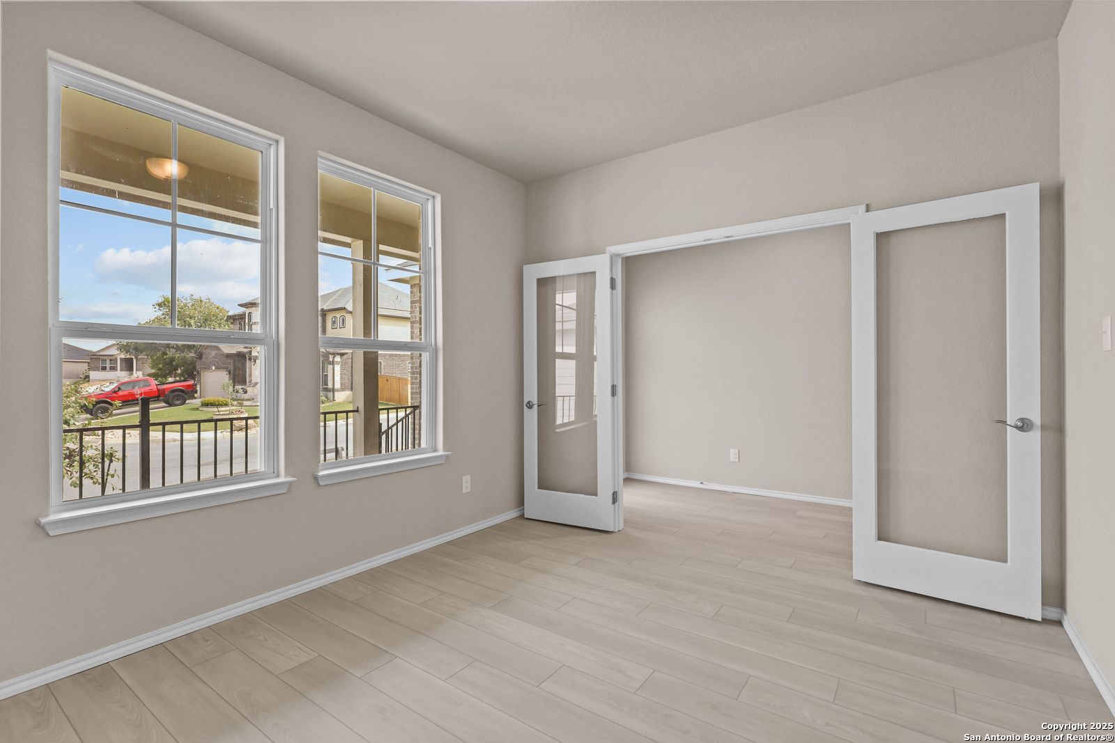 Bright home office with large windows, French doors, and wood floors in Davidson Homes Douglas G, San Antonio
