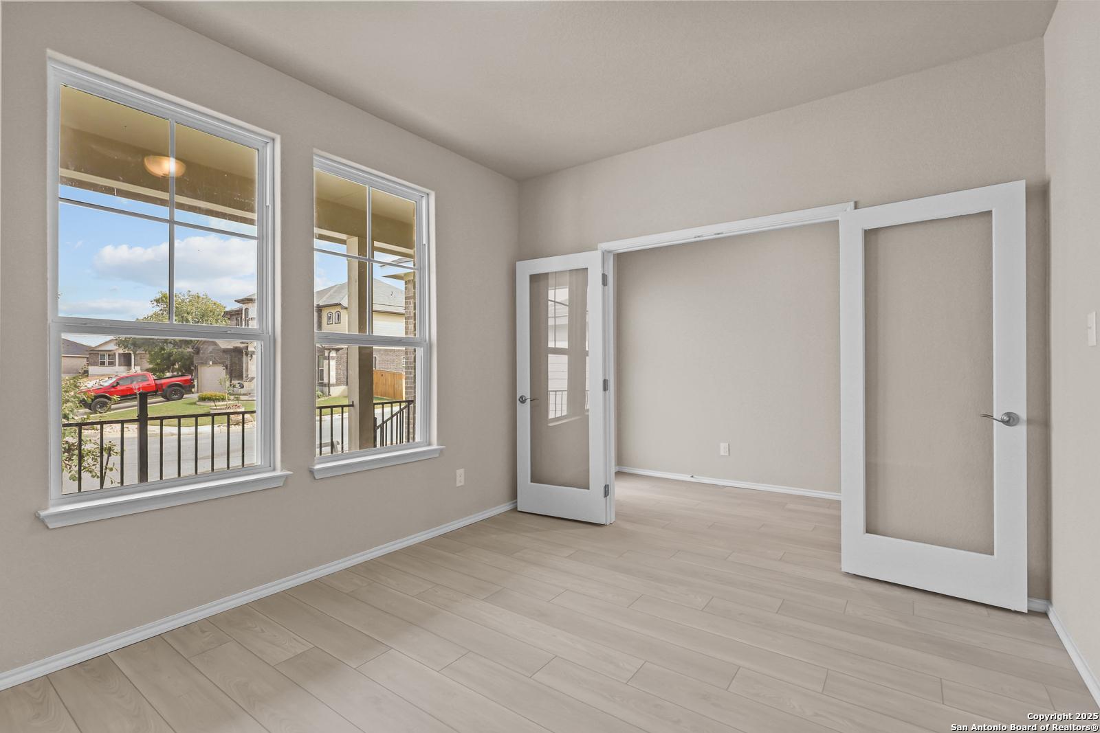 Bright home office with large windows, French doors, and wood floors in Davidson Homes Douglas G, San Antonio