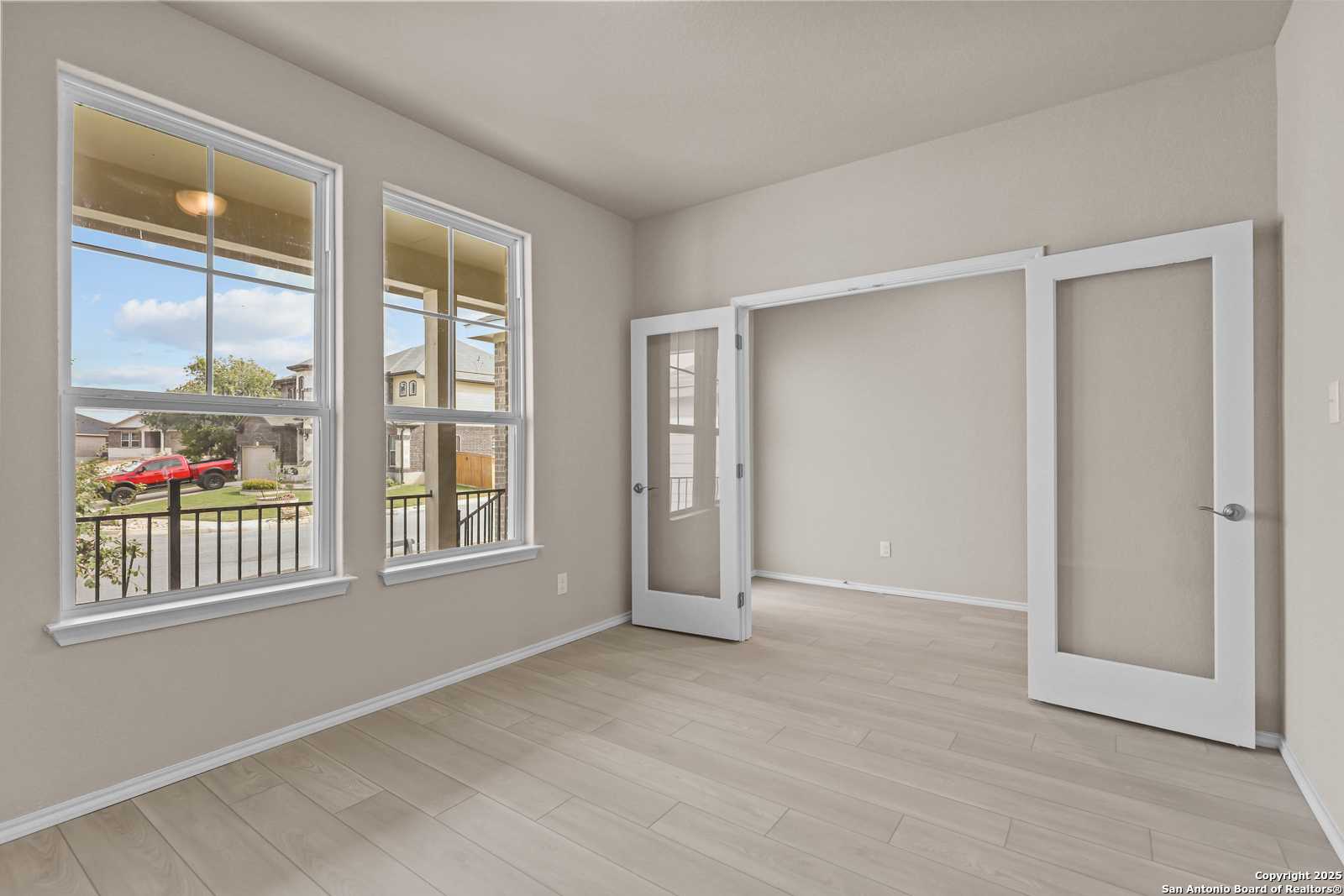 Bright home office with large windows, French doors, and wood floors in Davidson Homes Douglas G, San Antonio