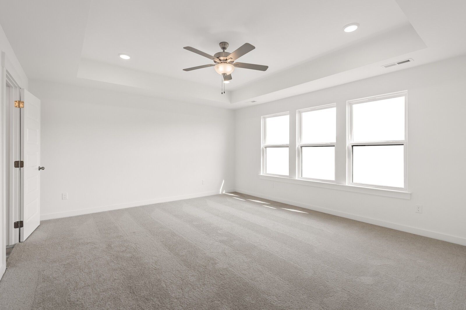 Bright secondary bedroom with three large windows, ceiling fan, recessed lights, and carpeted floor in The Willow D, Mt. Juliet