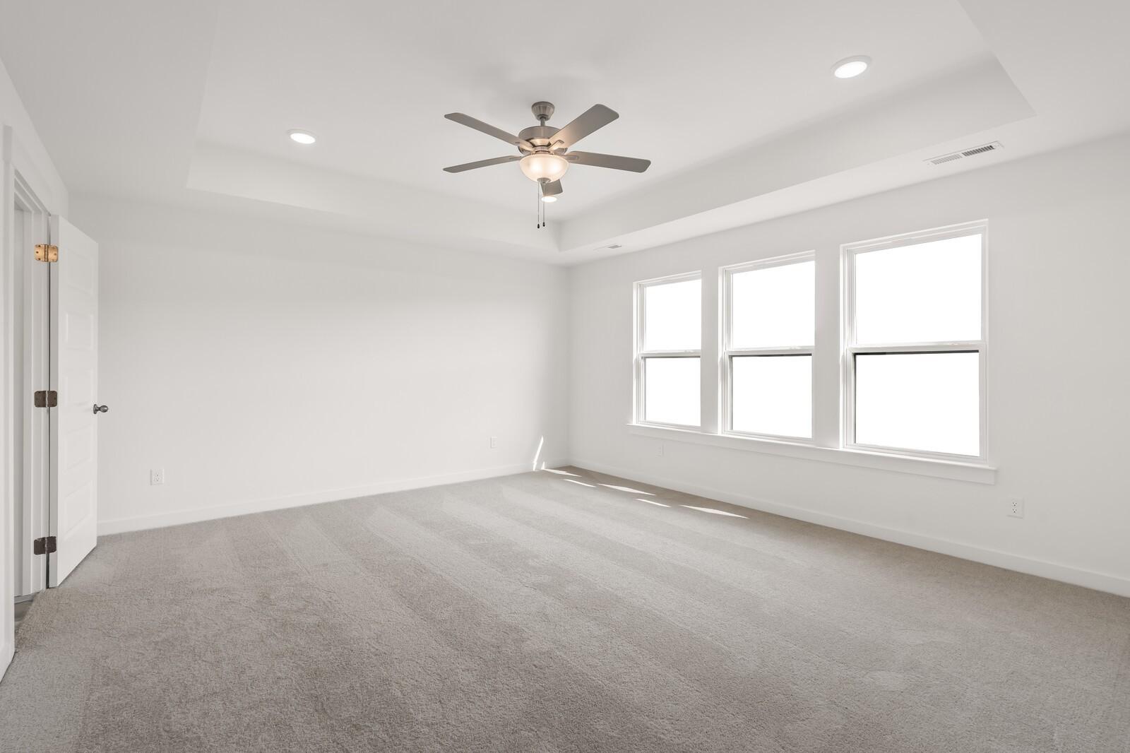 Bright secondary bedroom with three large windows, ceiling fan, recessed lights, and carpeted floor in The Willow D, Mt. Juliet