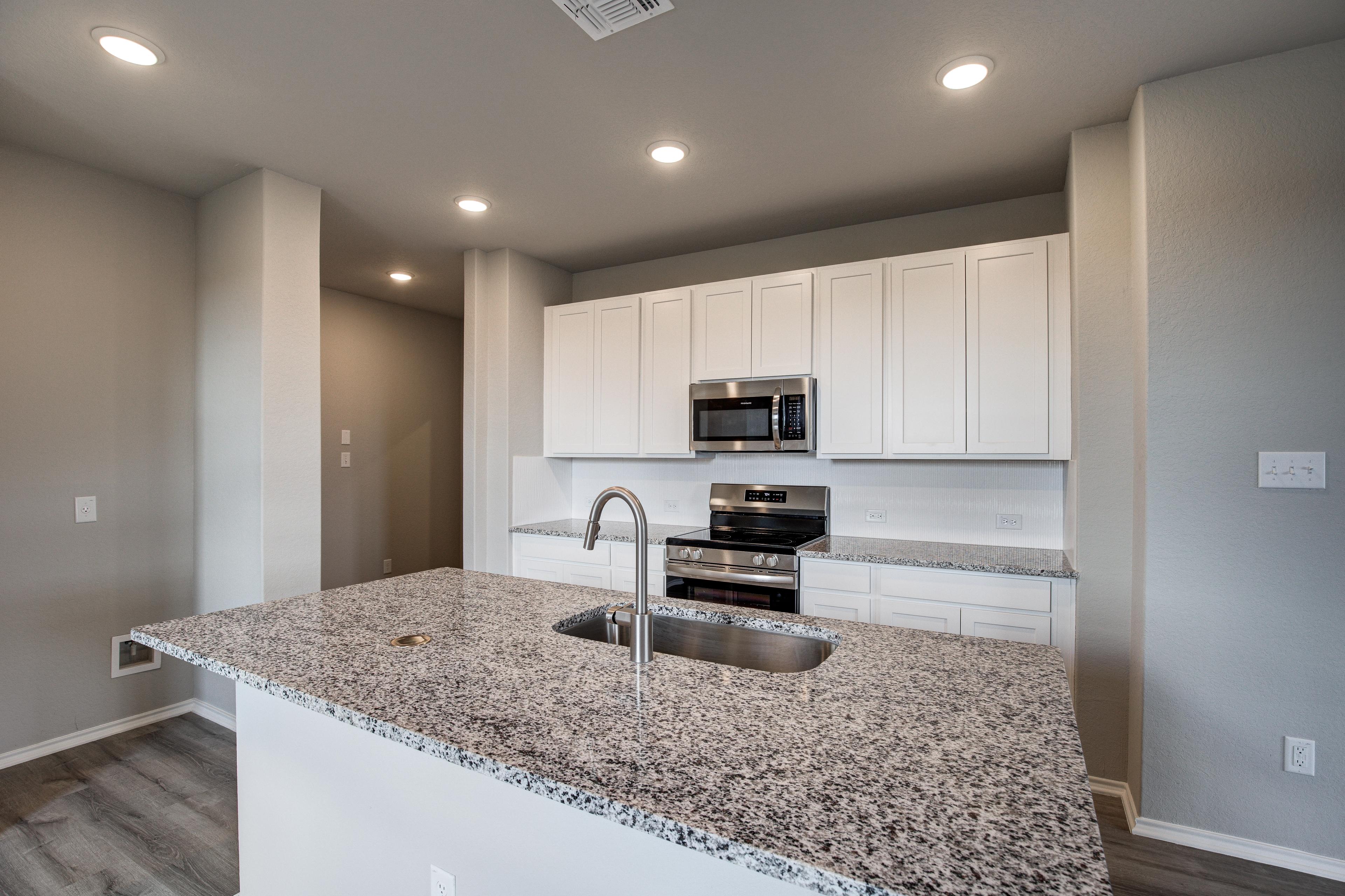 Spacious Blanco C kitchen with white shaker cabinets, granite island sink, stainless appliances, open layout in San Antonio home