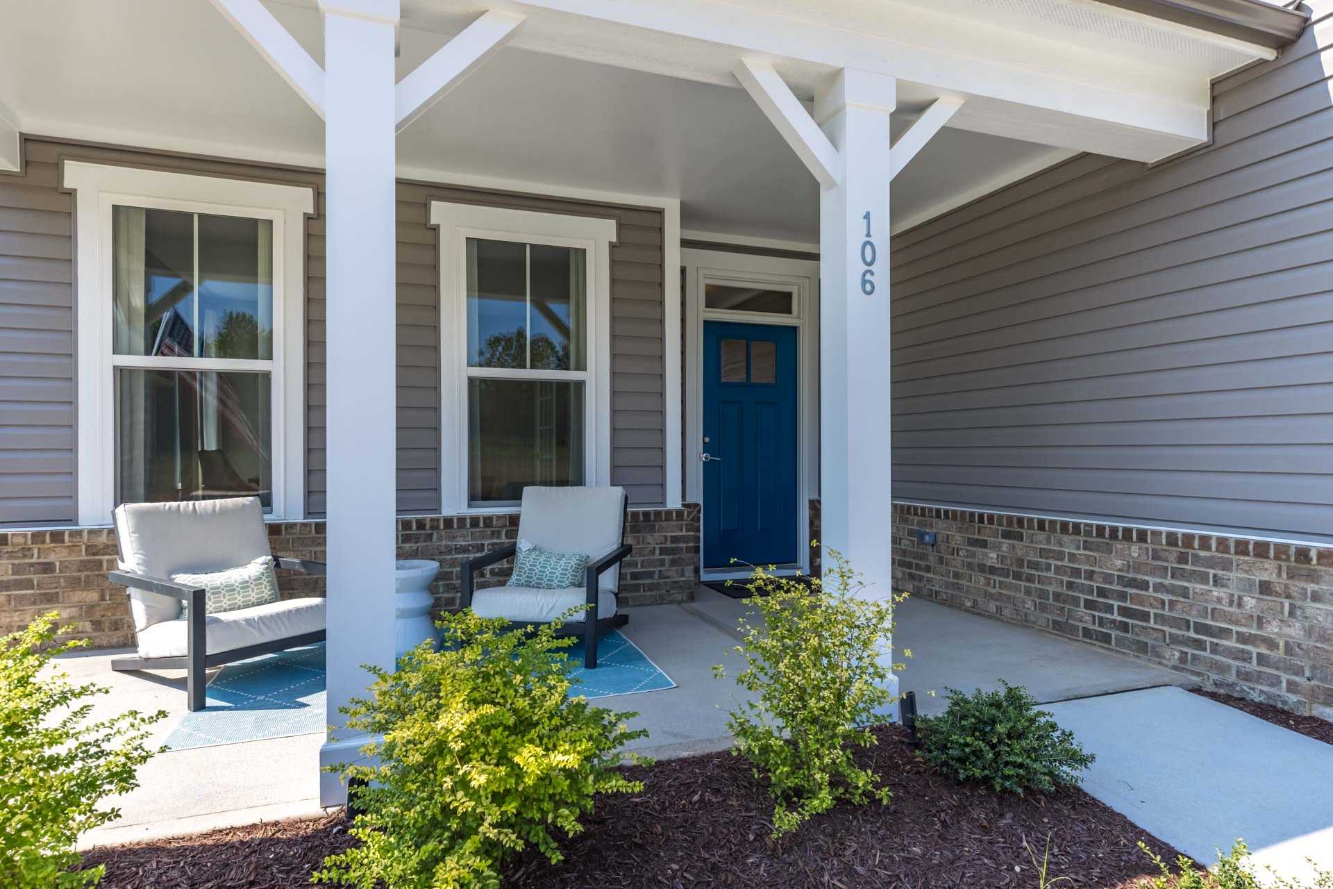 Charming gray craftsman home exterior in Highland Forest, Fuquay-Varina NC with covered porch, blue door, and Adirondack chairs