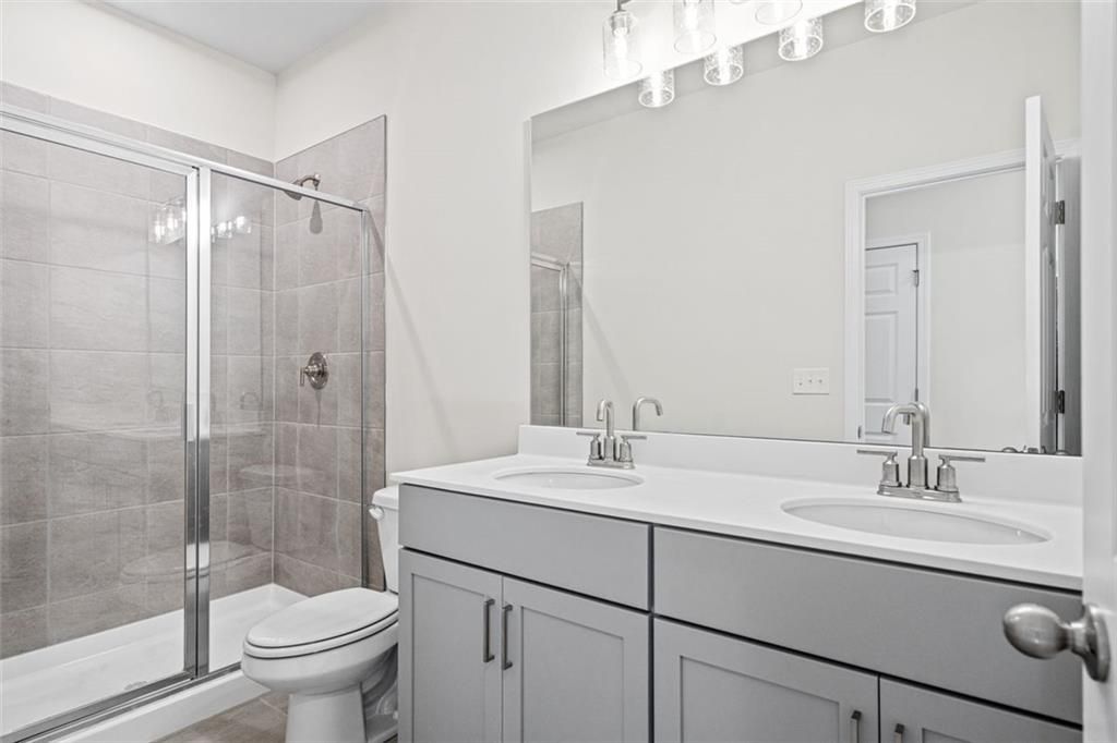 Elegant master bathroom with double gray vanity, frameless glass shower, and subway tile in Davidson Homes The Glenwood C at Wehunt Meadows, Hoschton