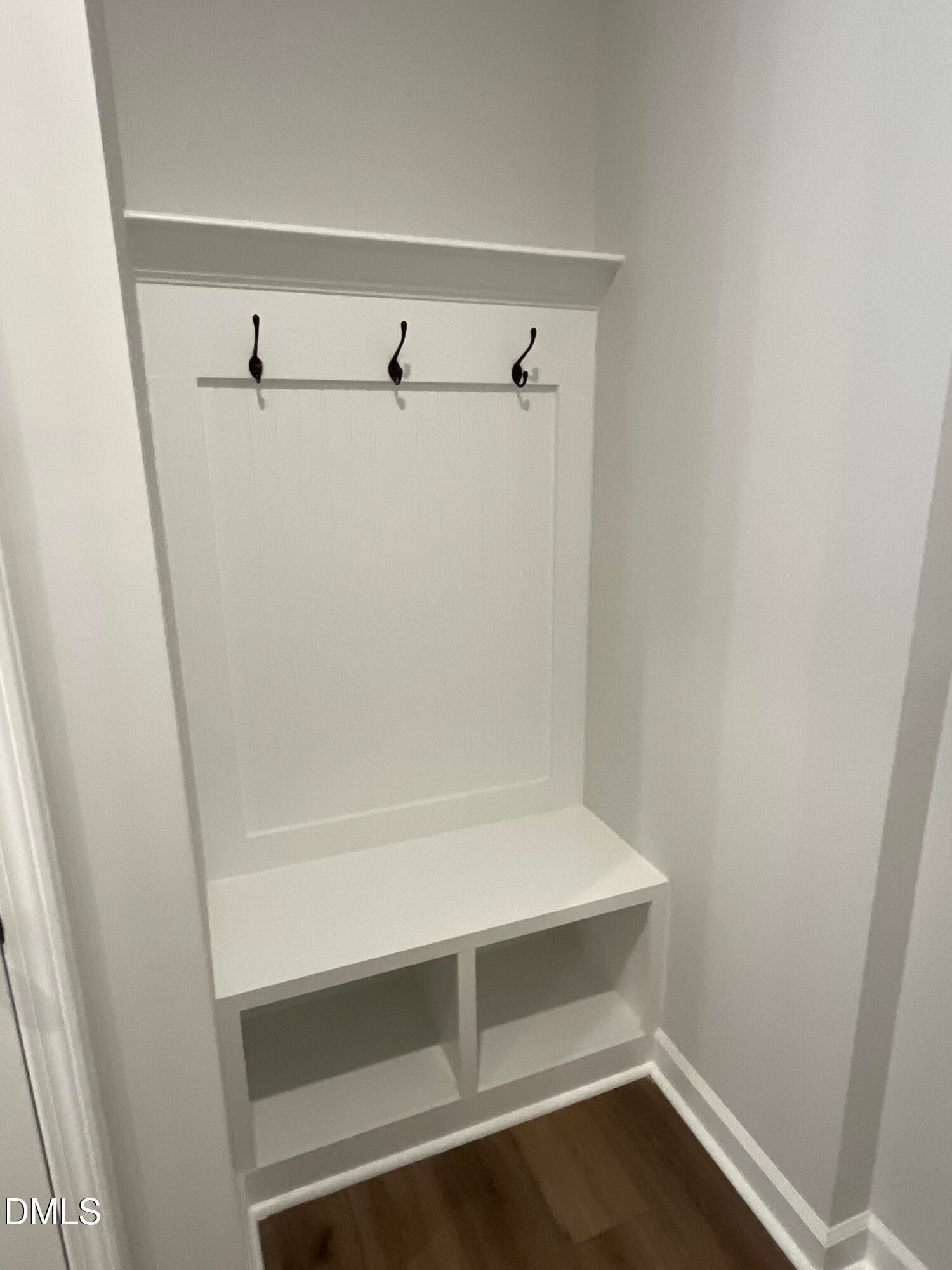 White mudroom bench with black coat hooks and shoe storage cubbies in Davidson Homes The Beech C, Wake Forest, NC