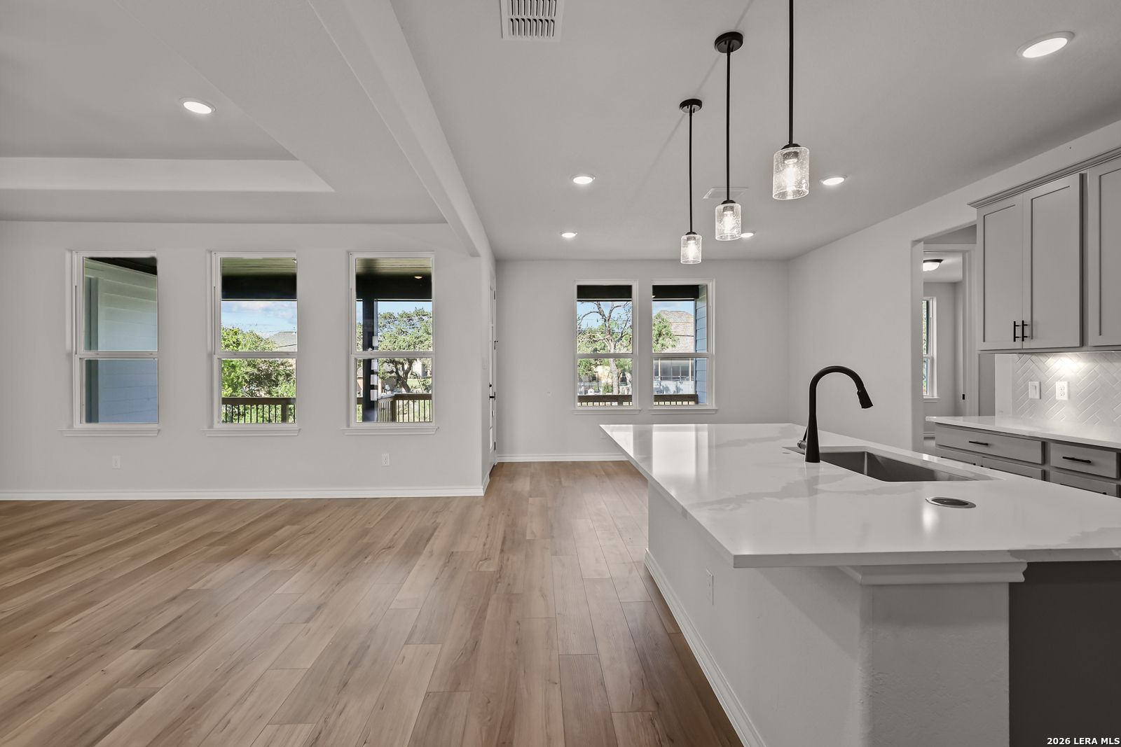 Open-concept kitchen with white quartz island, pendant lights, and hardwood-style flooring in Davidson Homes' Oxford F plan, Castroville