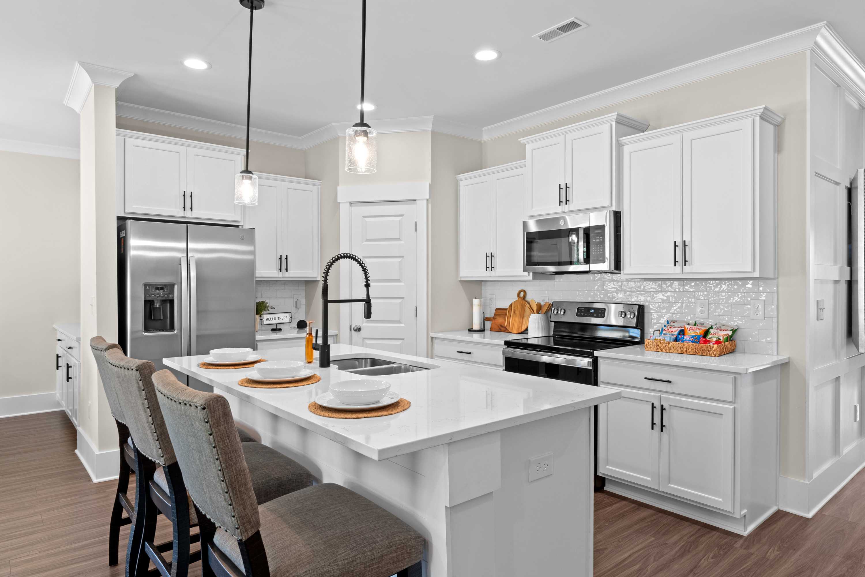 Spacious modern kitchen in Ivy Hills Toney Alabama with white shaker cabinets stainless steel appliances large island and hardwood floors