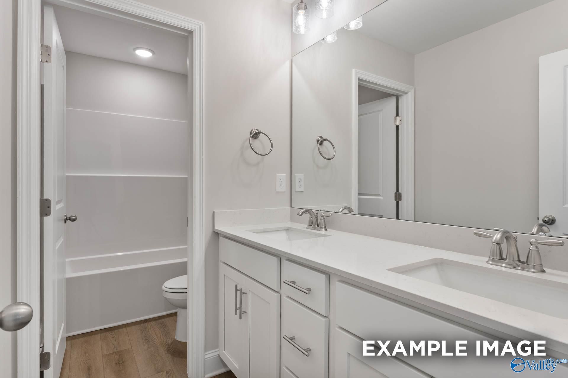 Modern double-sink vanity bathroom with tub, toilet, and open linen storage in Davidson Homes The Chelsea D, New Market, AL