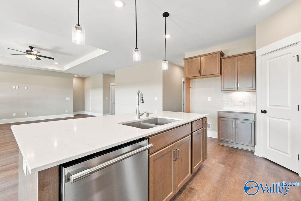 Modern kitchen with white quartz island, pendant lighting, and wood cabinets in The Rockford floor plan, Hartselle, AL.