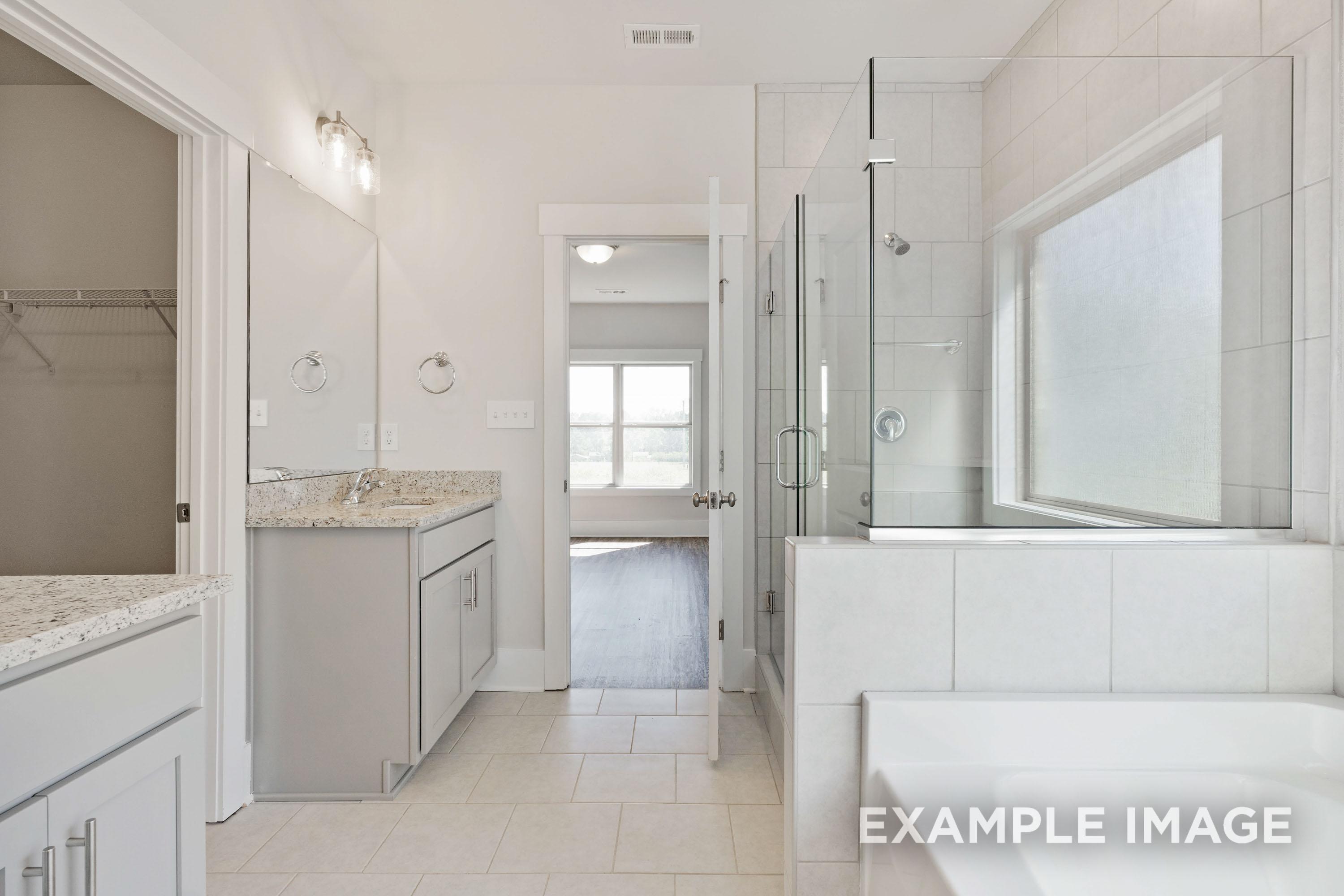 Master bathroom in The Richmond D featuring a granite vanity, glass-enclosed shower, and soaking tub in New Market, Alabama.