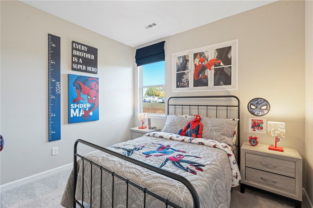 Spider-Man themed kids' bedroom with twin bed, posters, and growth chart in Davidson Homes The Phoenix B, Opelika, Alabama