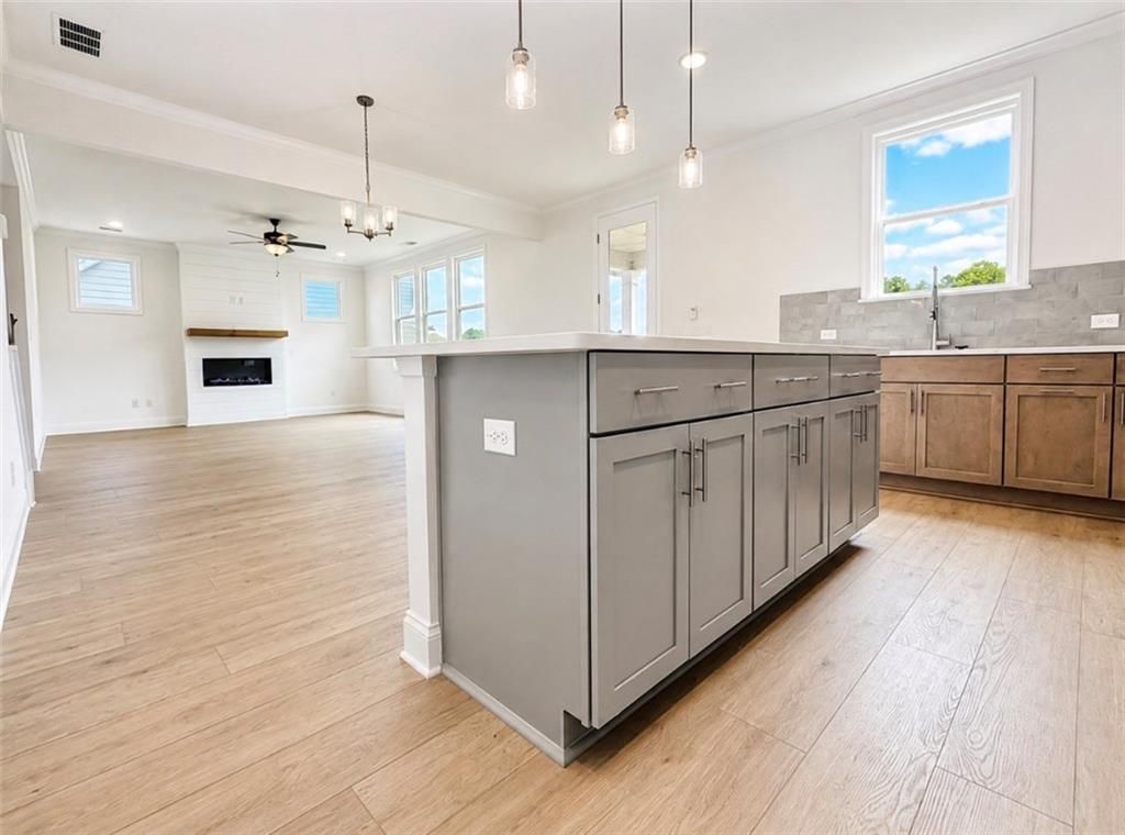 Open-concept kitchen with gray island overlooking living room and fireplace in Hickory C floor plan, Wehunt Meadows, Hoschton.