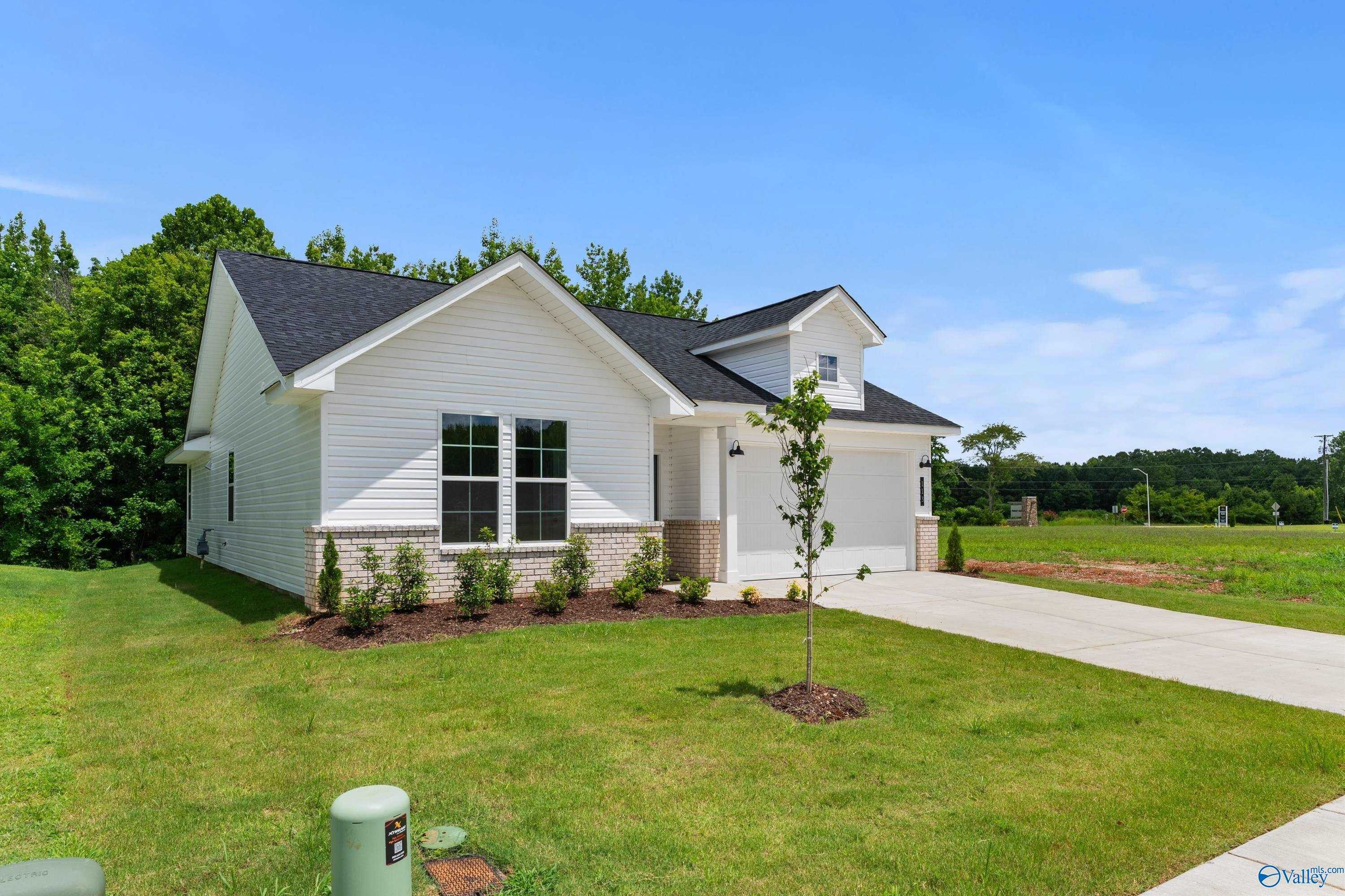Modern white single-story 3-bedroom home with 2-car garage and black roof in Forest Glen, Hazel Green, Alabama