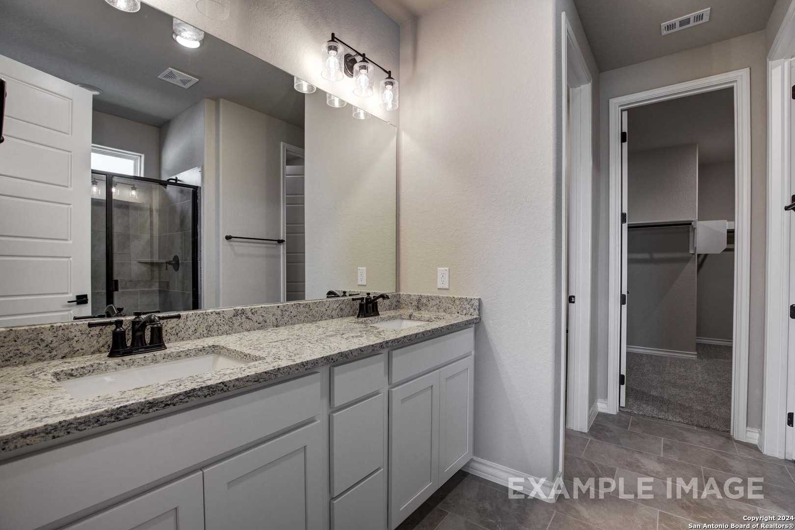 Luxurious master bathroom with double granite vanity, frameless glass shower, and soft lighting in Davidson Homes The Rockford G, Ladera San Antonio