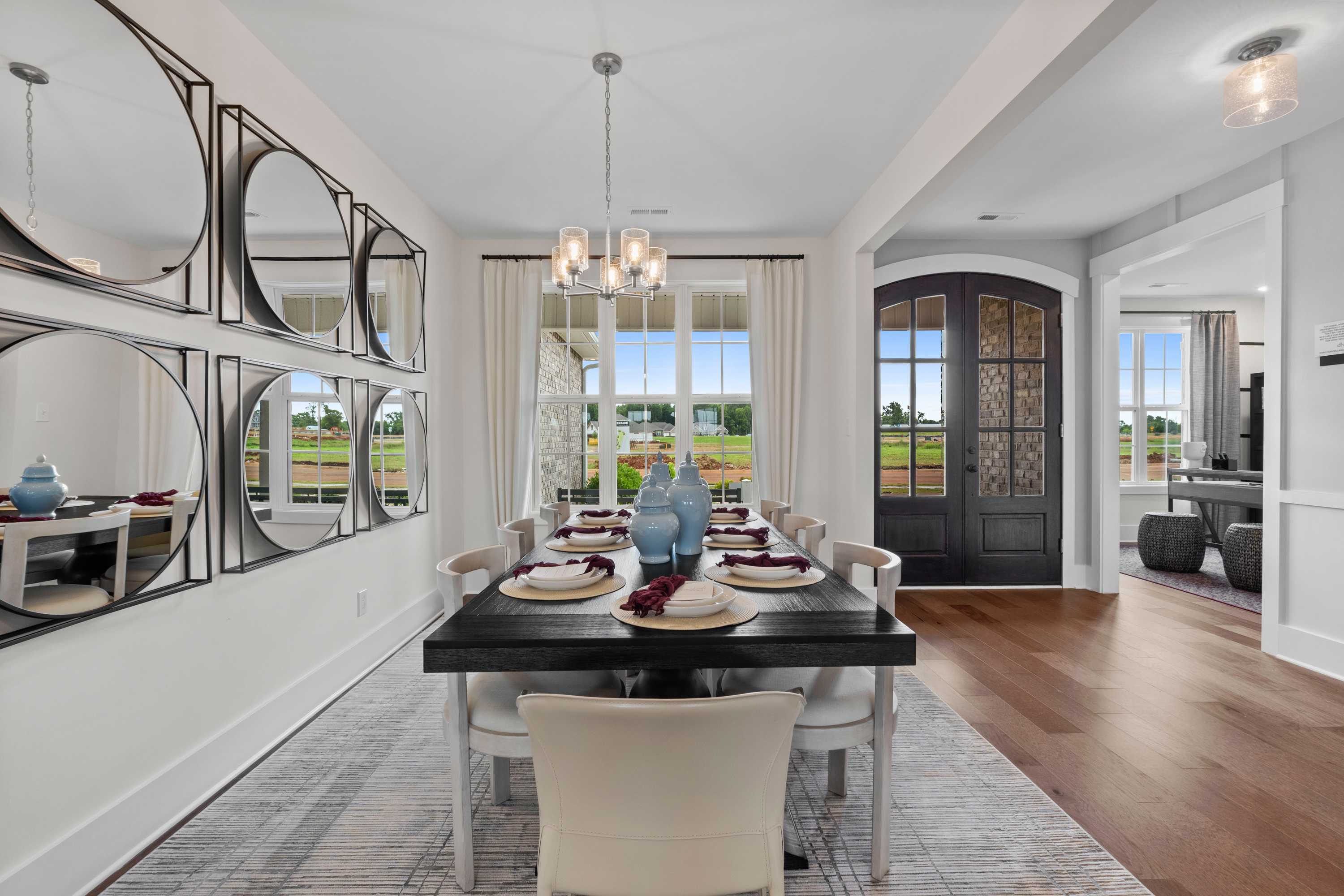Elegant dining room at Creekside in Harvest Alabama with wooden table blue vases mirrors chandelier and window views