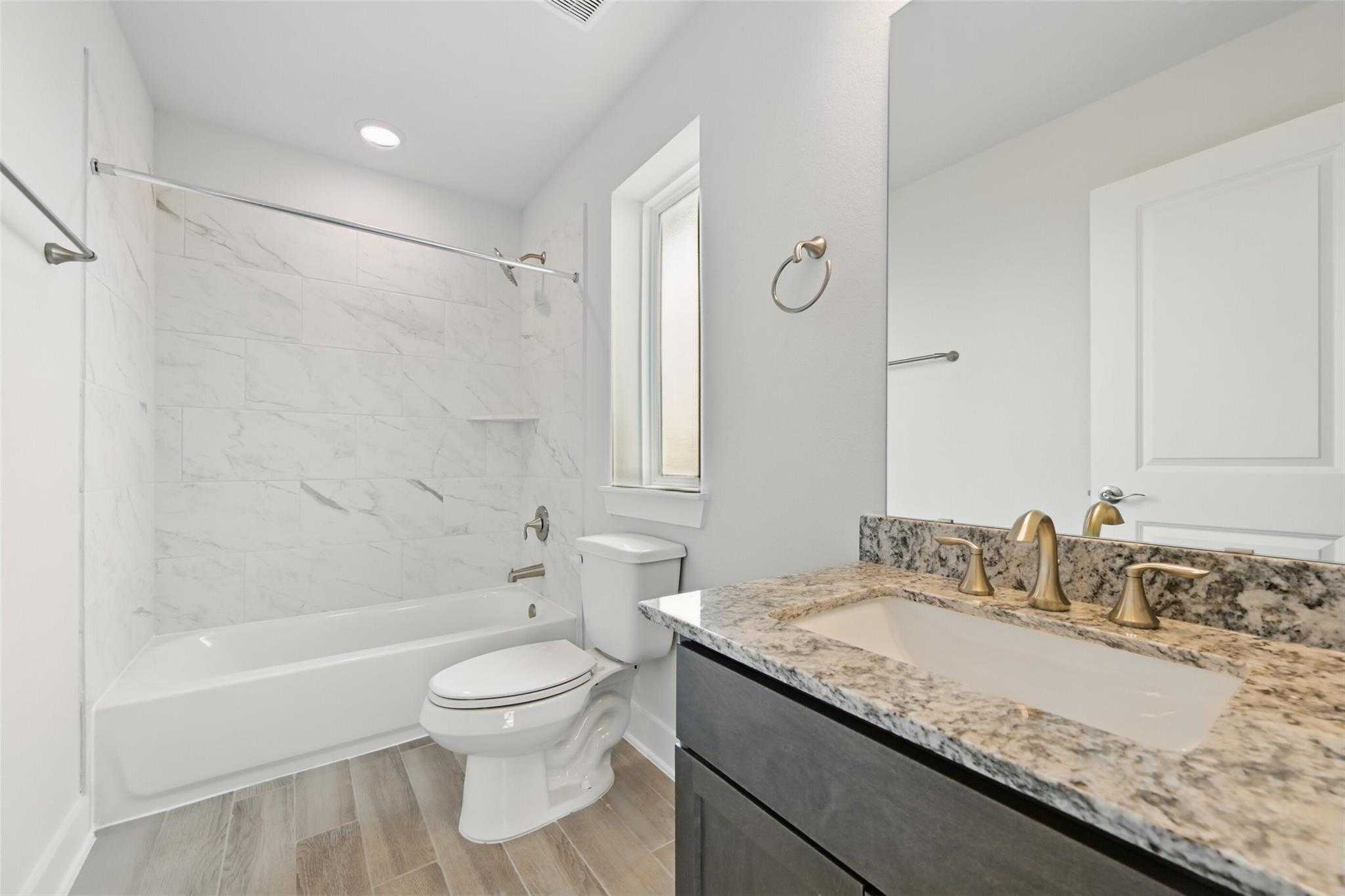 Modern bathroom with marble shower, soaking tub, gold fixtures, and quartz vanity in Davidson Homes The Philip A, Lago Mar, Texas City