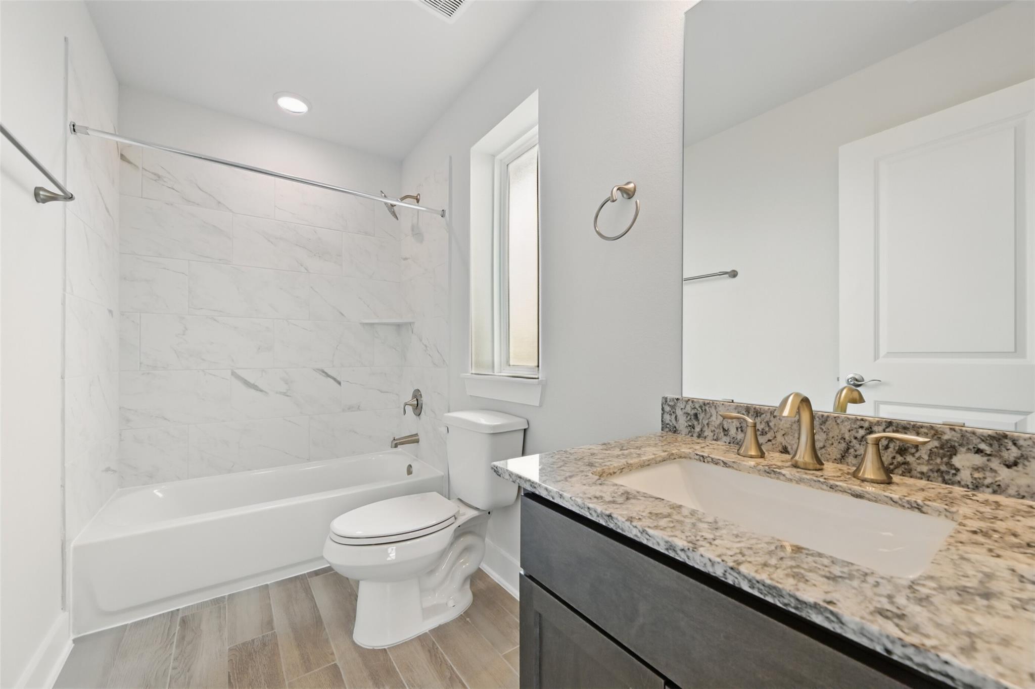 Modern bathroom with marble shower, soaking tub, gold fixtures, and quartz vanity in Davidson Homes The Philip A, Lago Mar, Texas City
