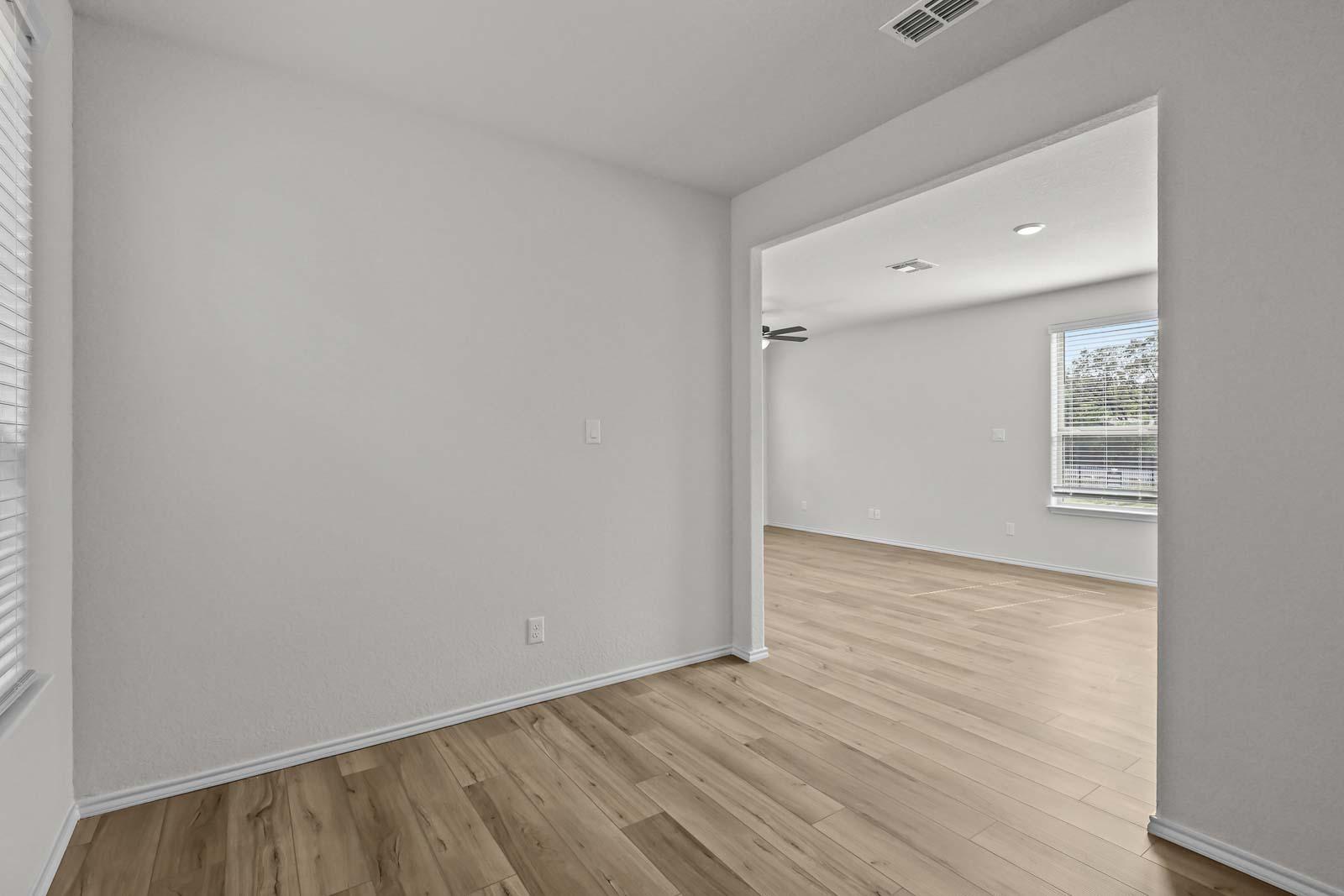 Open-concept living space in The Florence B home featuring neutral walls and light wood-style flooring in San Antonio.