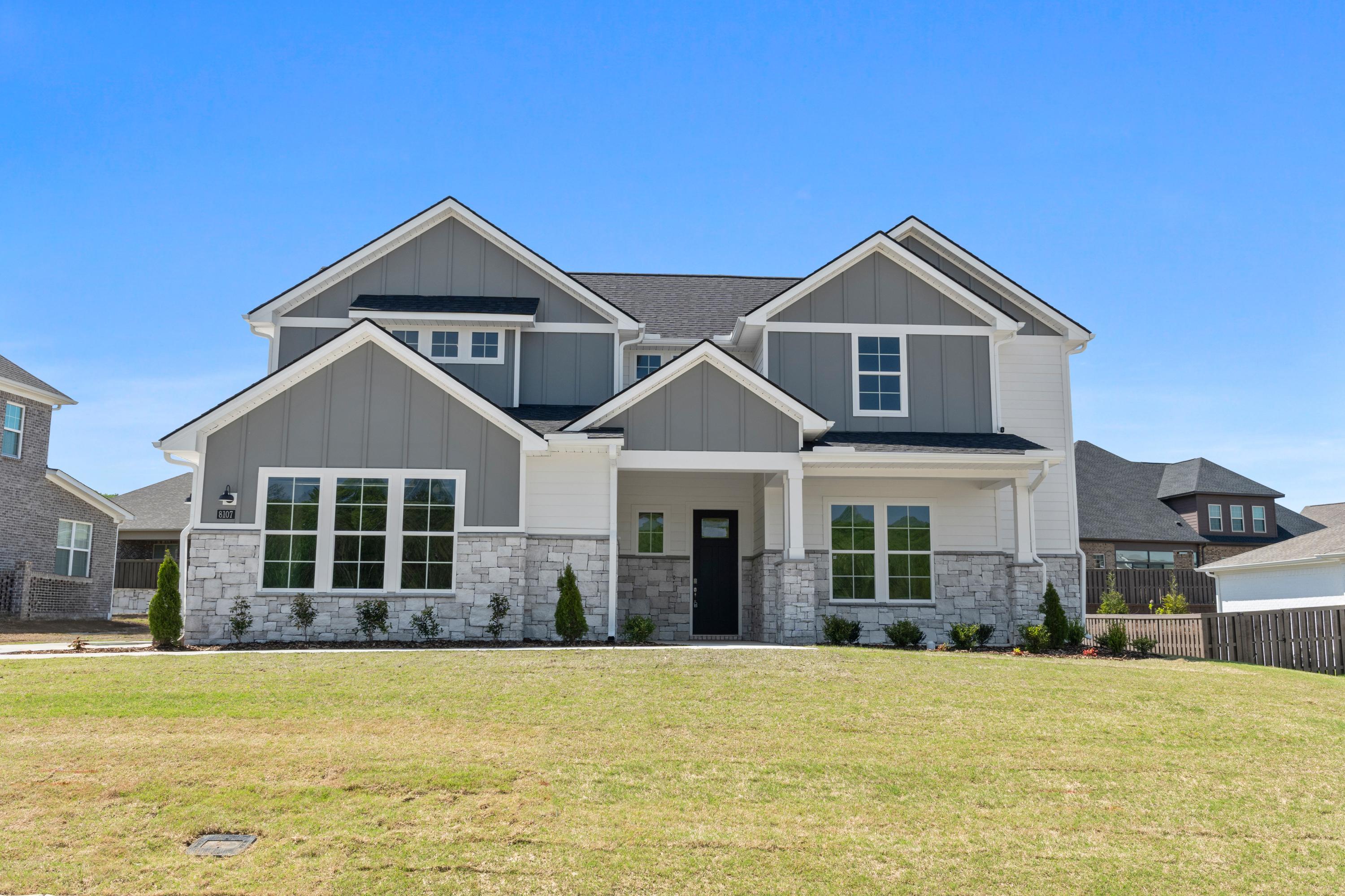 Modern single-story elevation of The Haven D with gray siding, stone base, large windows, and covered front porch