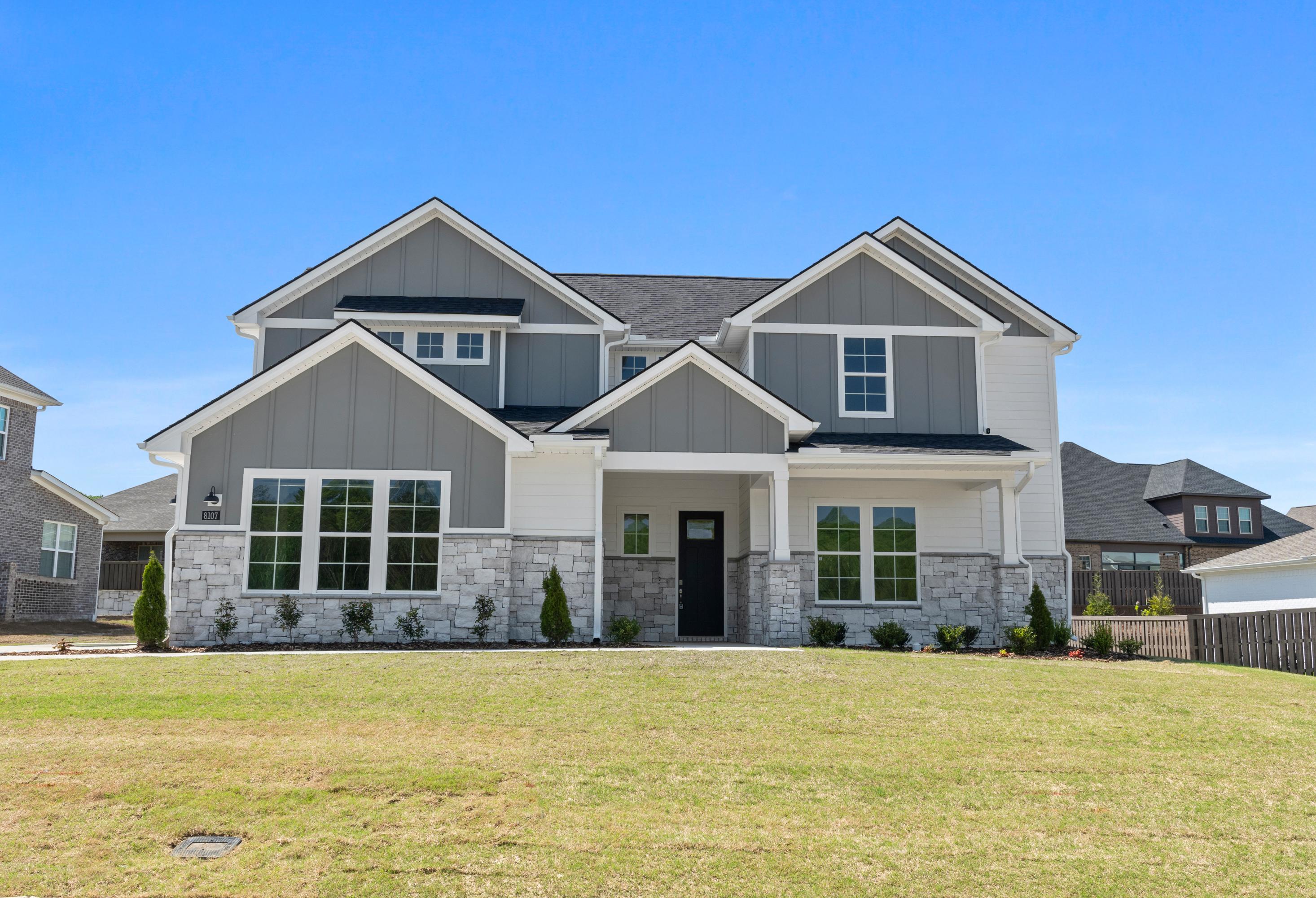 Modern single-story elevation of The Haven D with gray siding, stone base, large windows, and covered front porch