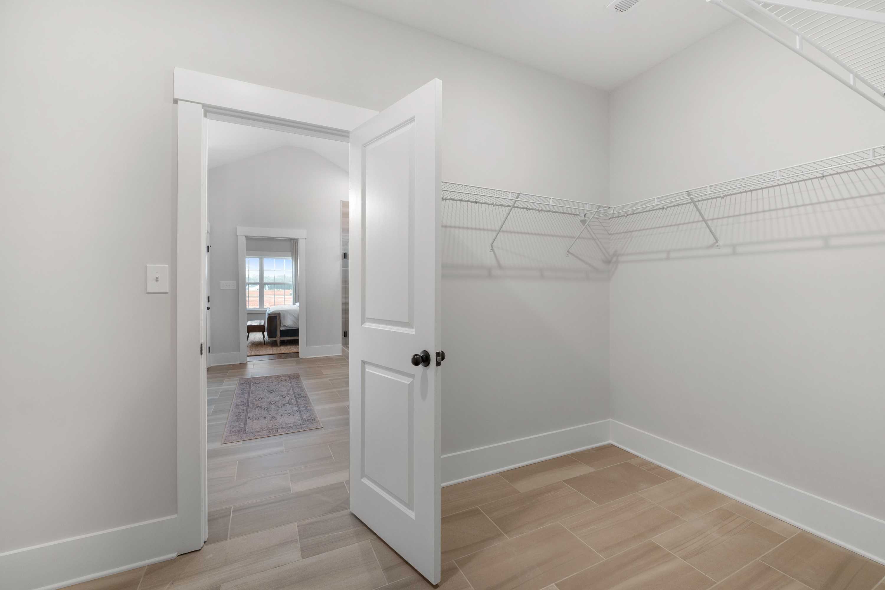 Spacious walk-in closet in Briercreek home, Meridianville AL by Davidson Homes, with wire shelving, hanging rods, and light wood floors