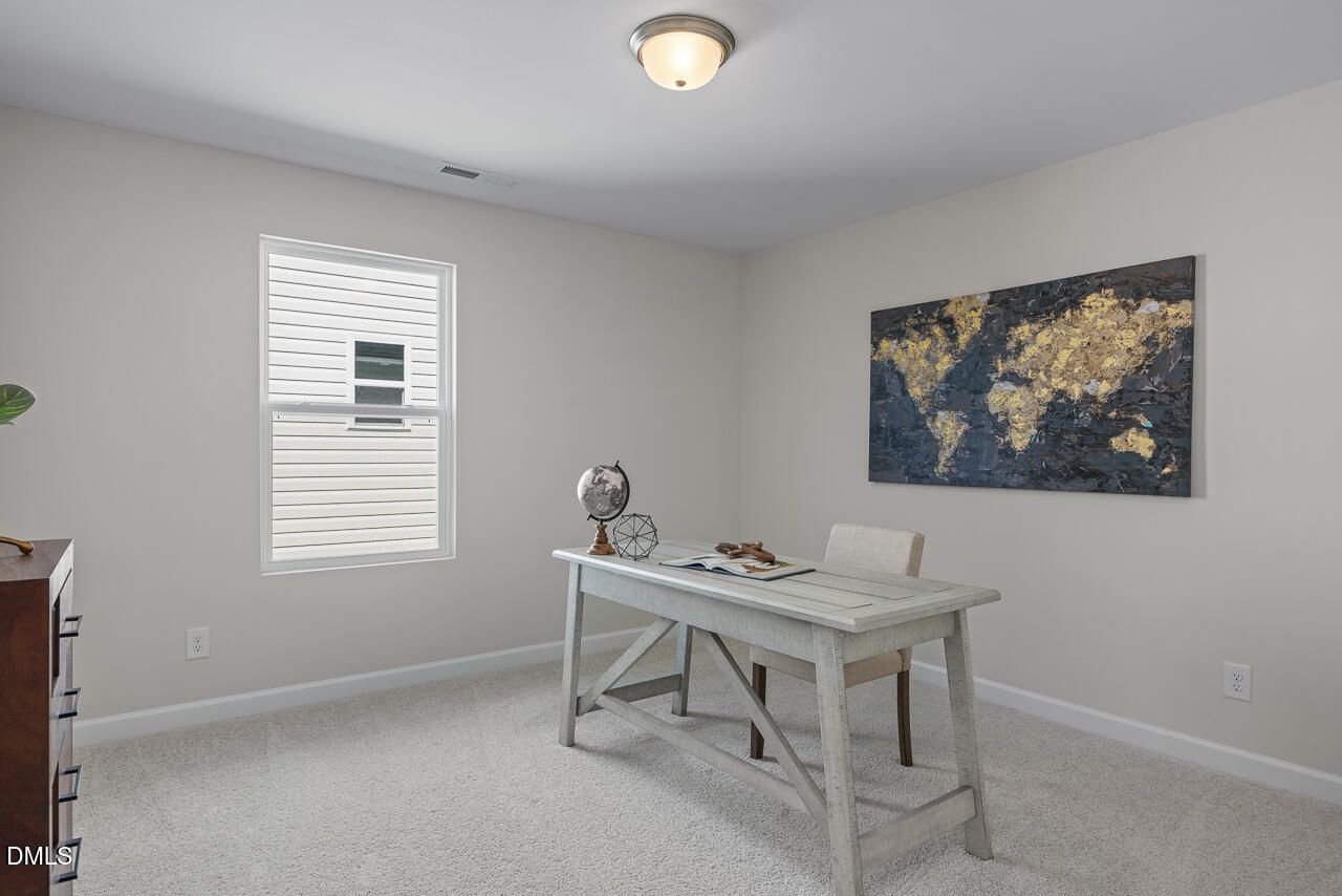 Cozy home office with world map artwork, farmhouse desk, globe, and beige walls in Davidson Homes The Preston A, Lillington, NC