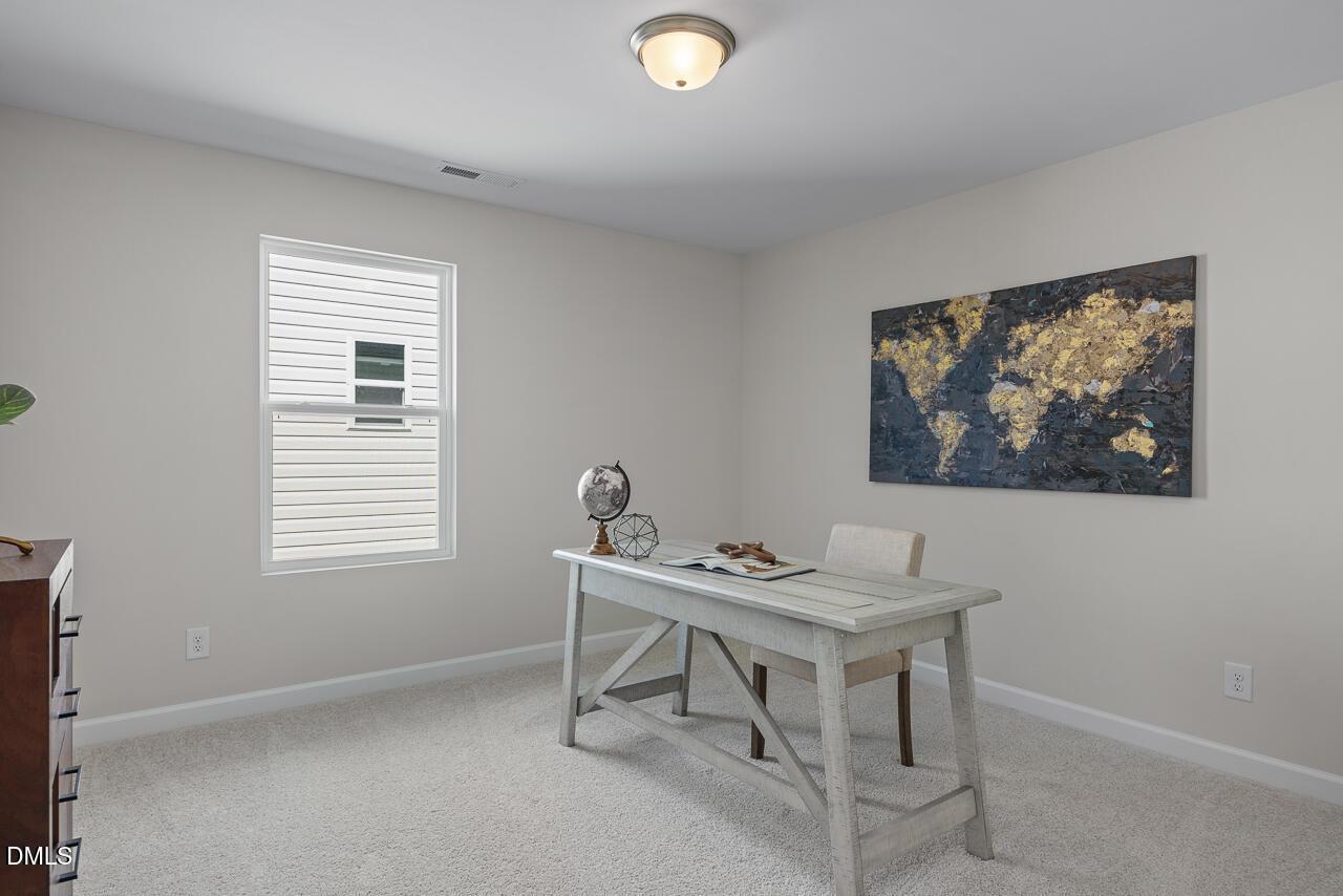Cozy home office with world map artwork, farmhouse desk, globe, and beige walls in Davidson Homes The Preston A, Lillington, NC