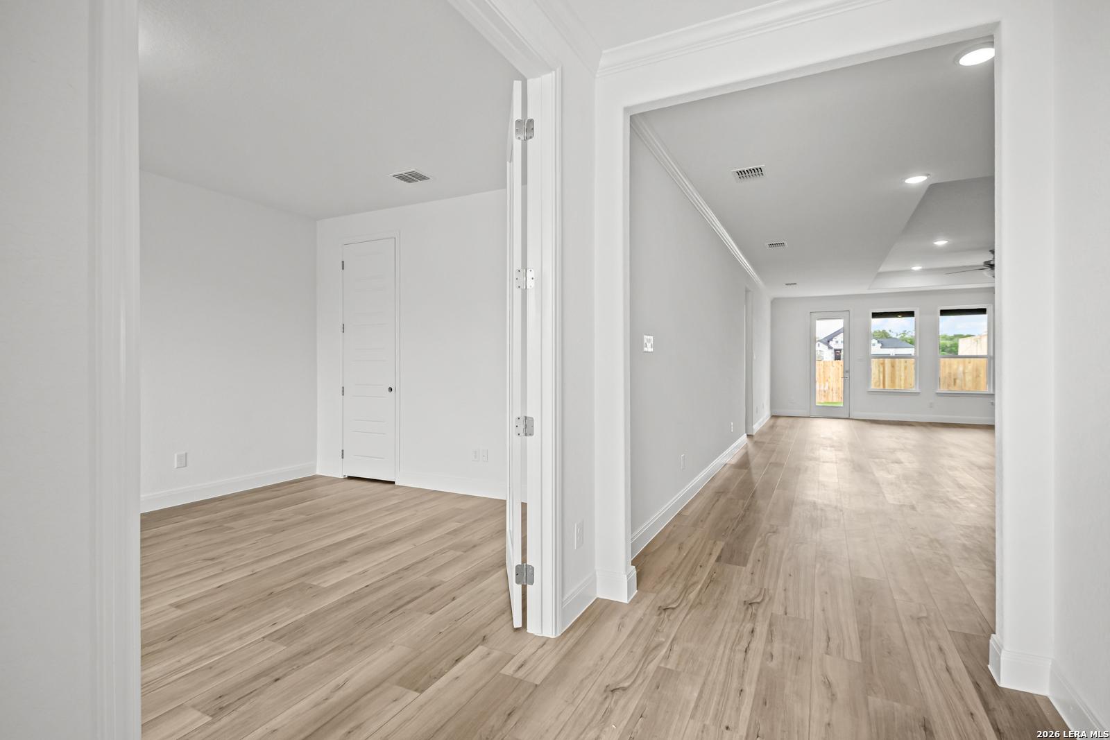 Bright, open-concept floor plan with wood-look flooring in The Lanier G home by Davidson Homes in Castroville, Texas.