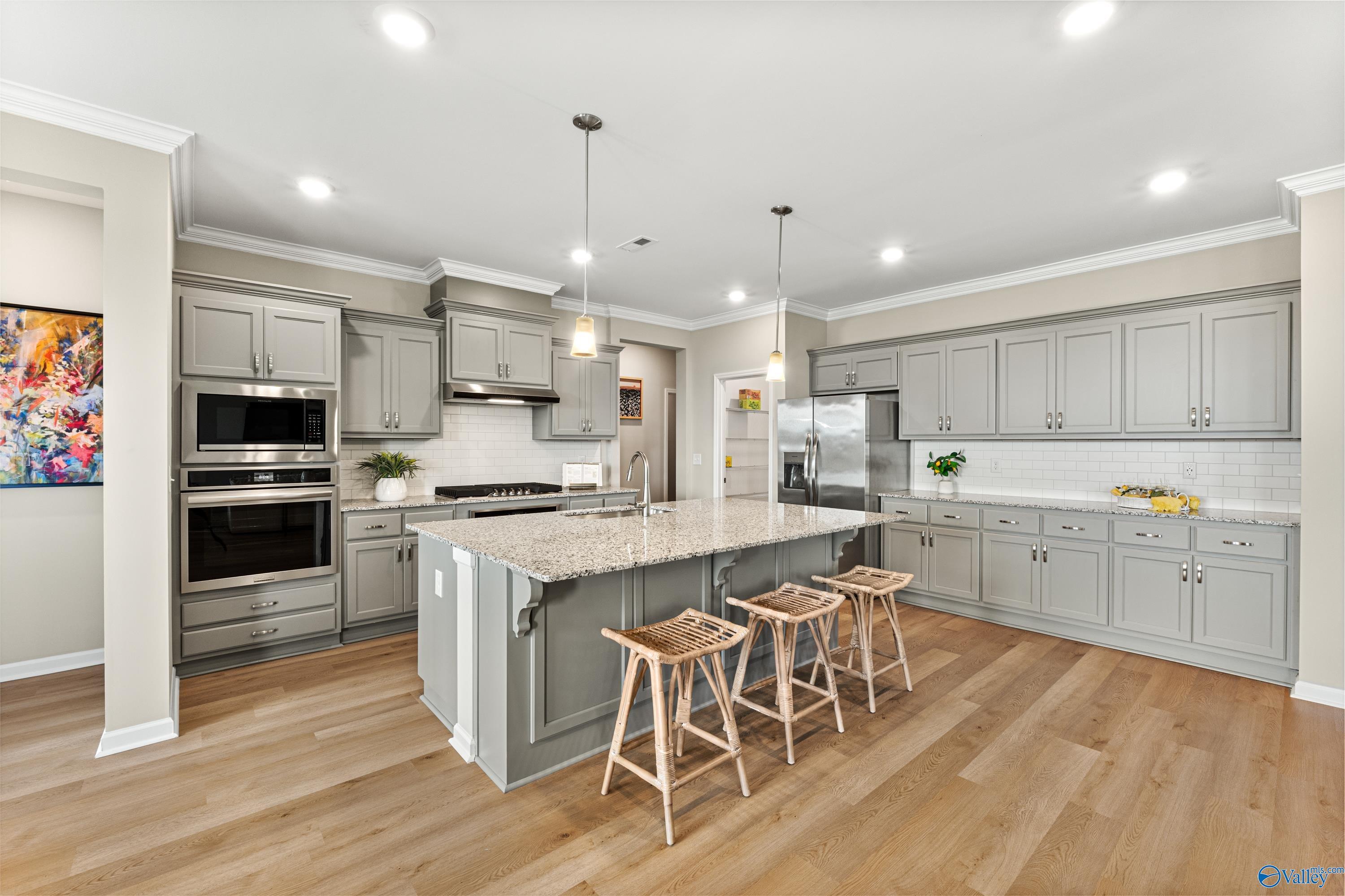 Modern gray shaker kitchen with granite island, stainless double oven, pendant lights in Davidson Homes The Sanctuary, Athens AL