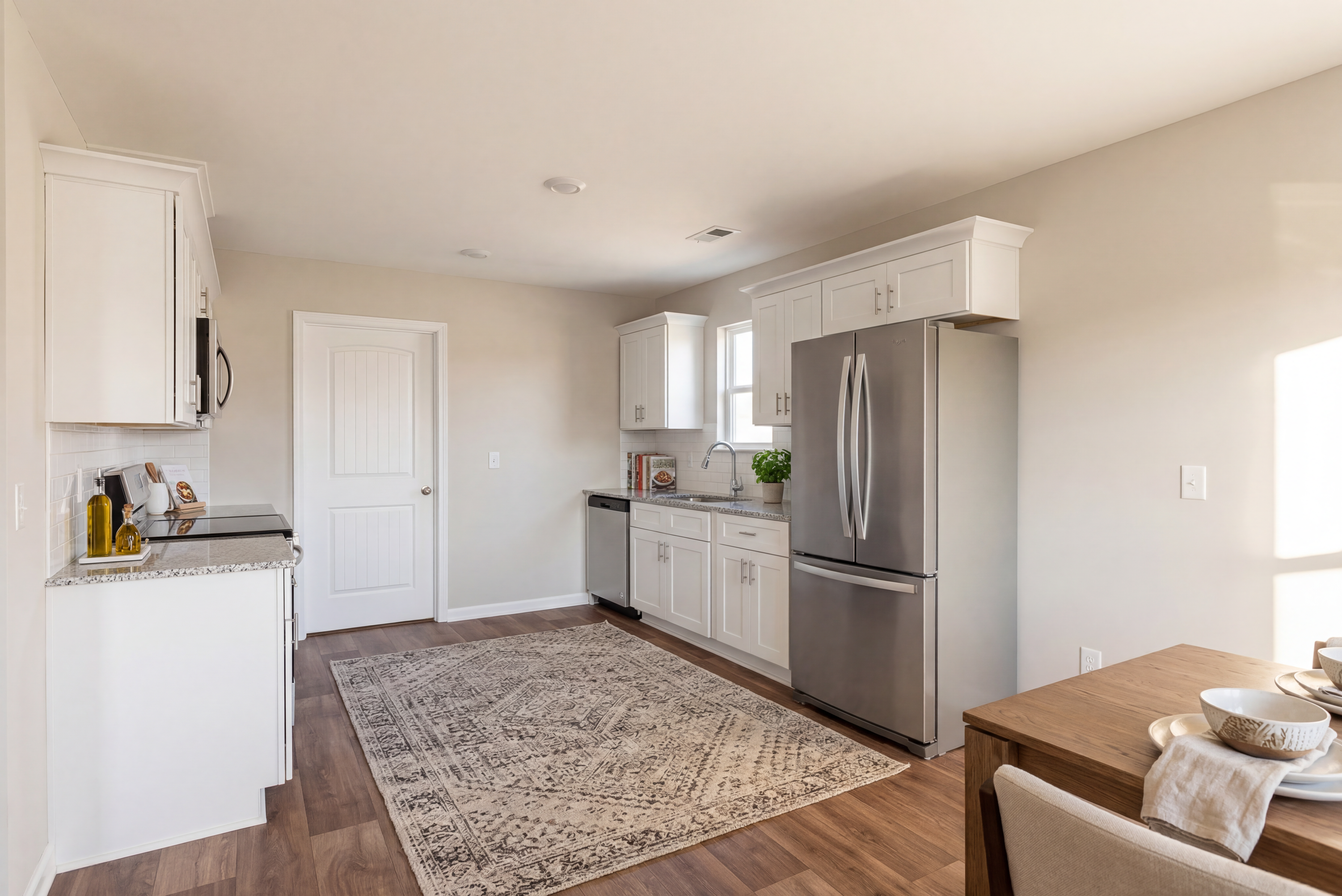 Spacious kitchen in Summer Vineyard, Phenix City AL with white shaker cabinets, stainless steel fridge, granite counters and hardwood floors