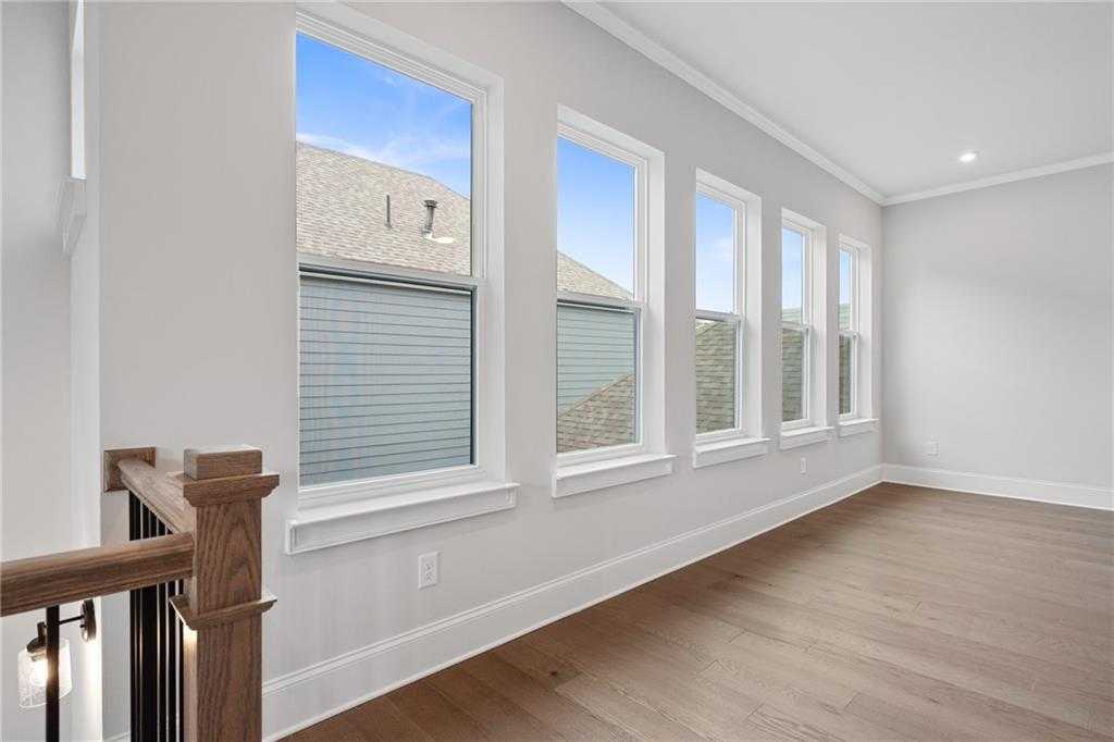 Bright upstairs hallway with large windows, hardwood floors, and wooden railing in Davidson Homes The Seaside B, Woodstock, Georgia