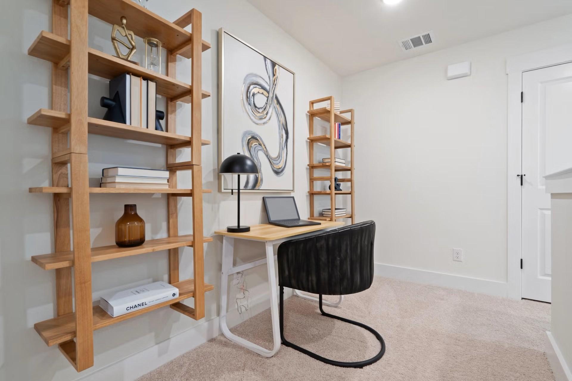 Modern home office with wooden open shelves, abstract art, sleek desk, laptop, and black chair in Davidson Homes The Wake D, Wylie, Texas