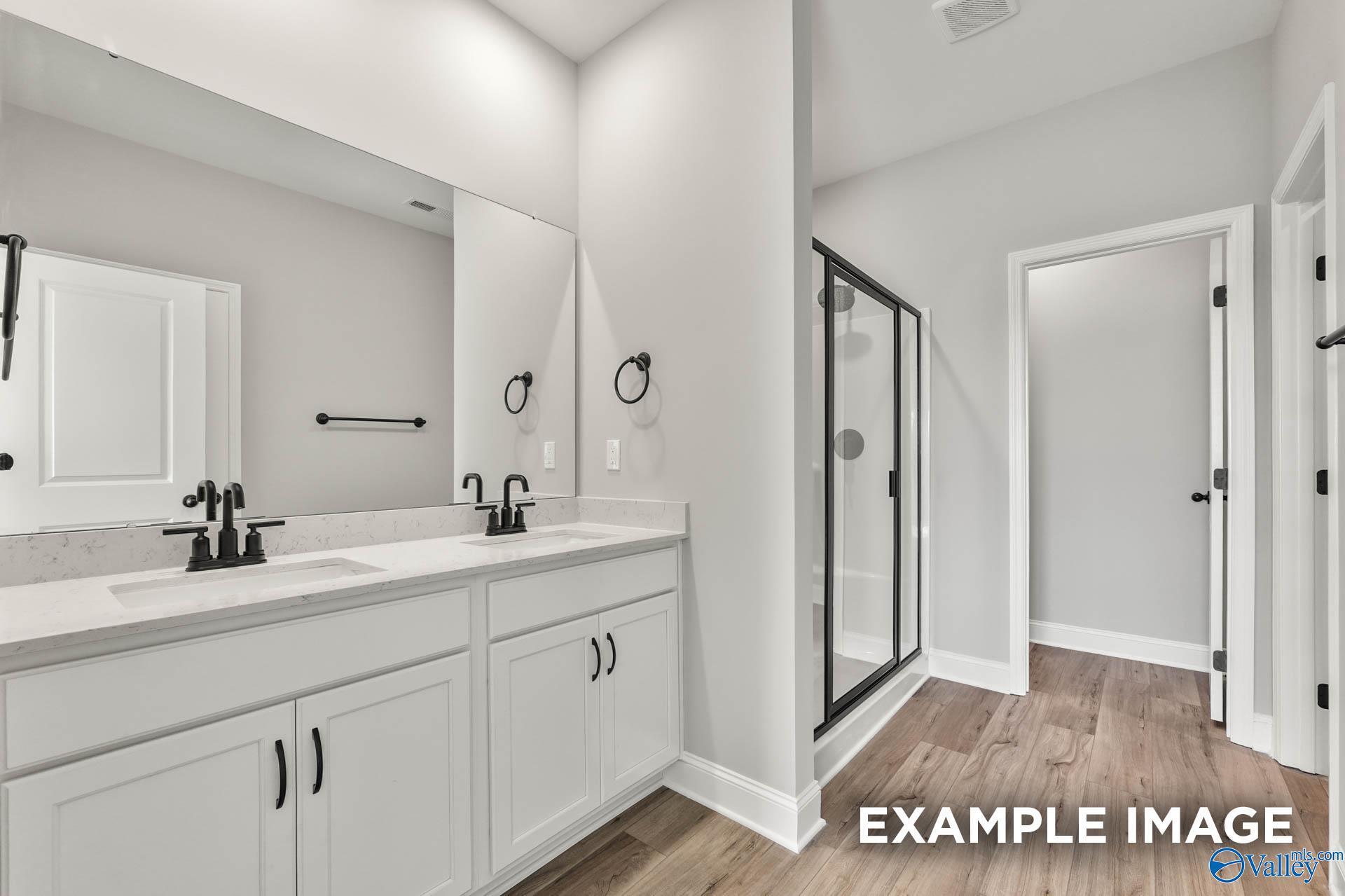 Modern master bathroom featuring double vanity with white cabinets and glass walk-in shower in Davidson Homes The Daphne C, Athens, Alabama