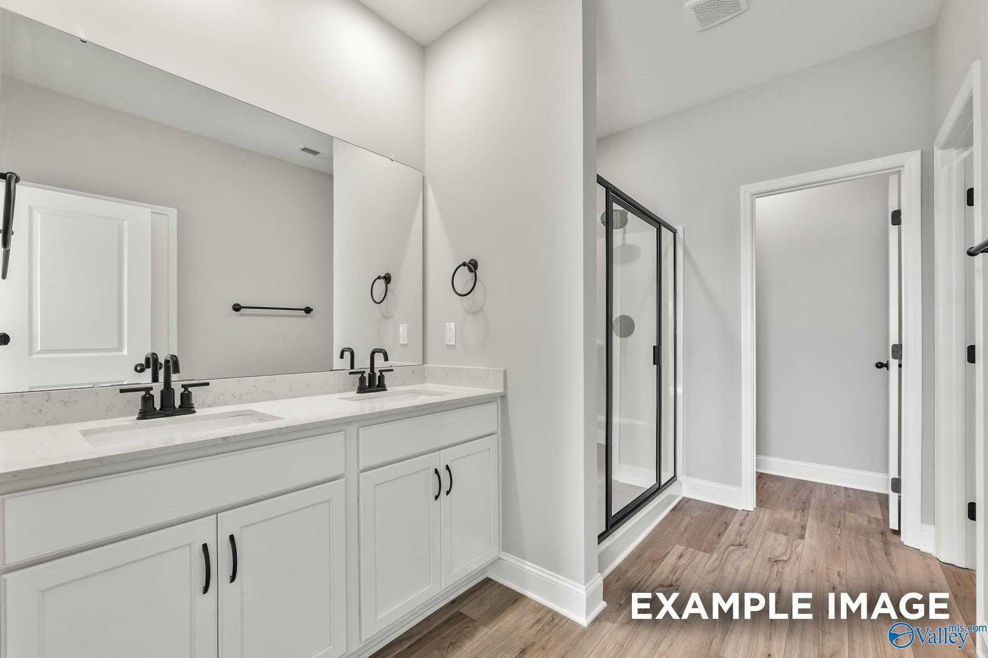 Modern master bathroom featuring double vanity with white cabinets and glass walk-in shower in Davidson Homes The Daphne C, Athens, Alabama