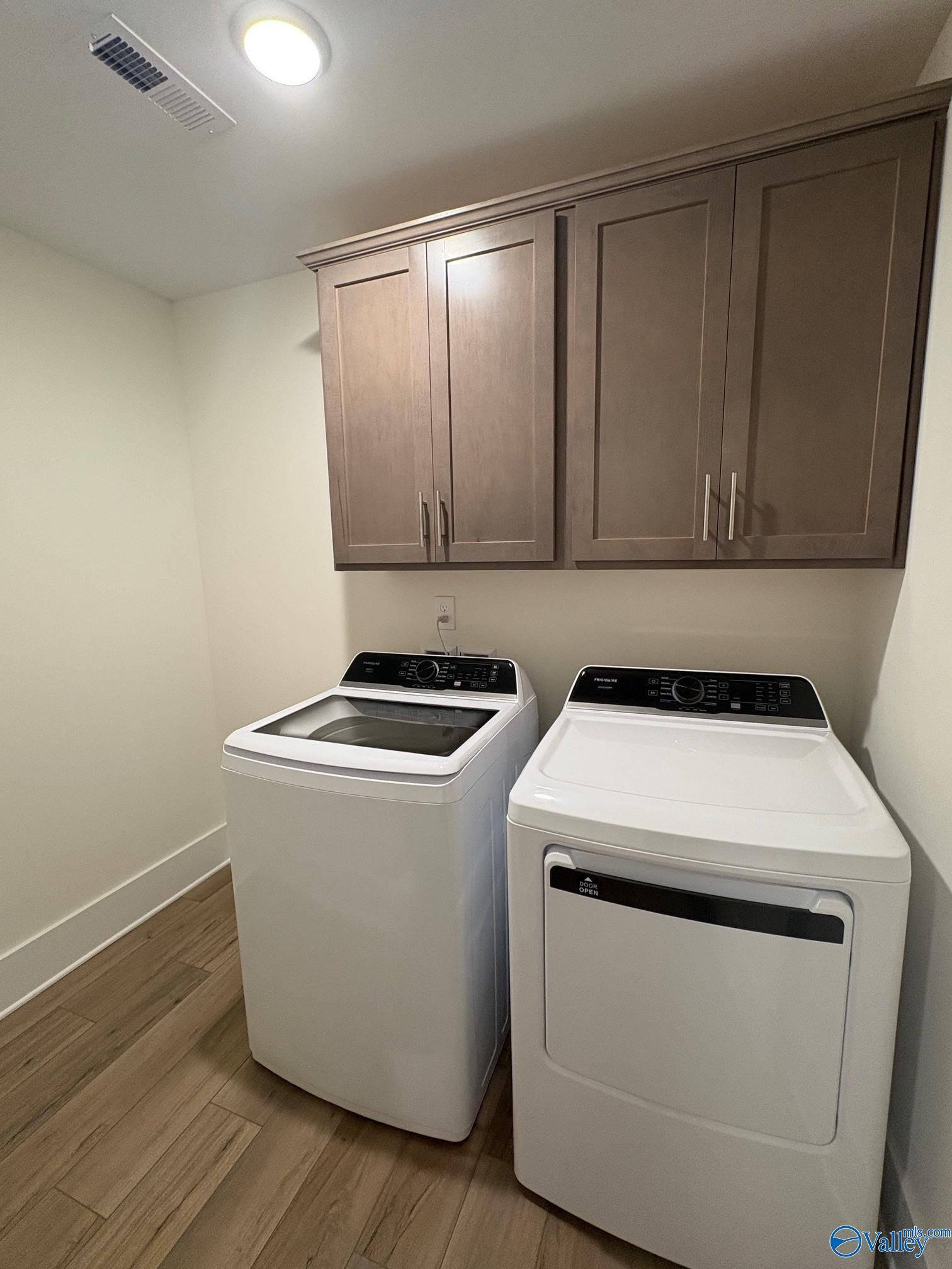 Spacious laundry room featuring white washer dryer set and light wood cabinets in The Daphne C 4-bedroom home, Arab, Alabama